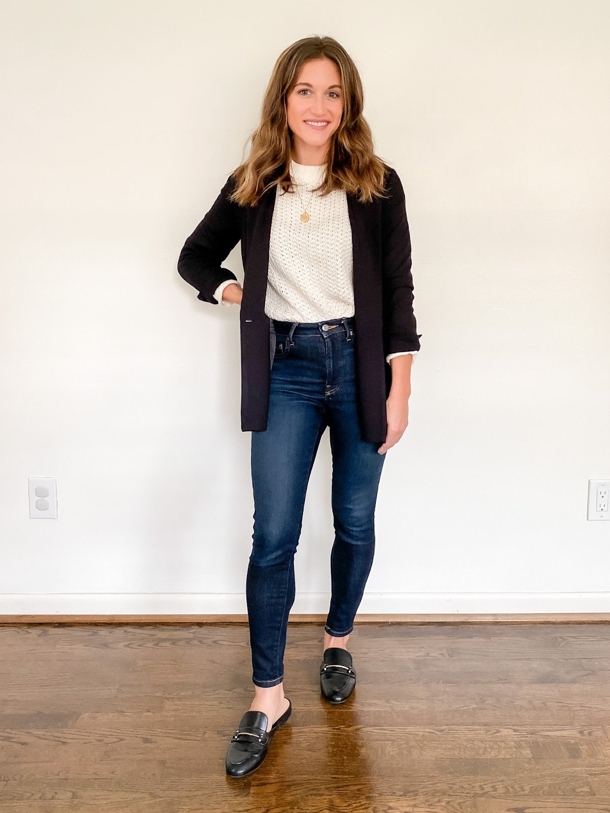 ashley wearing a cream sweater under a black blazer, dark wash skinny jeans and black backless loafers