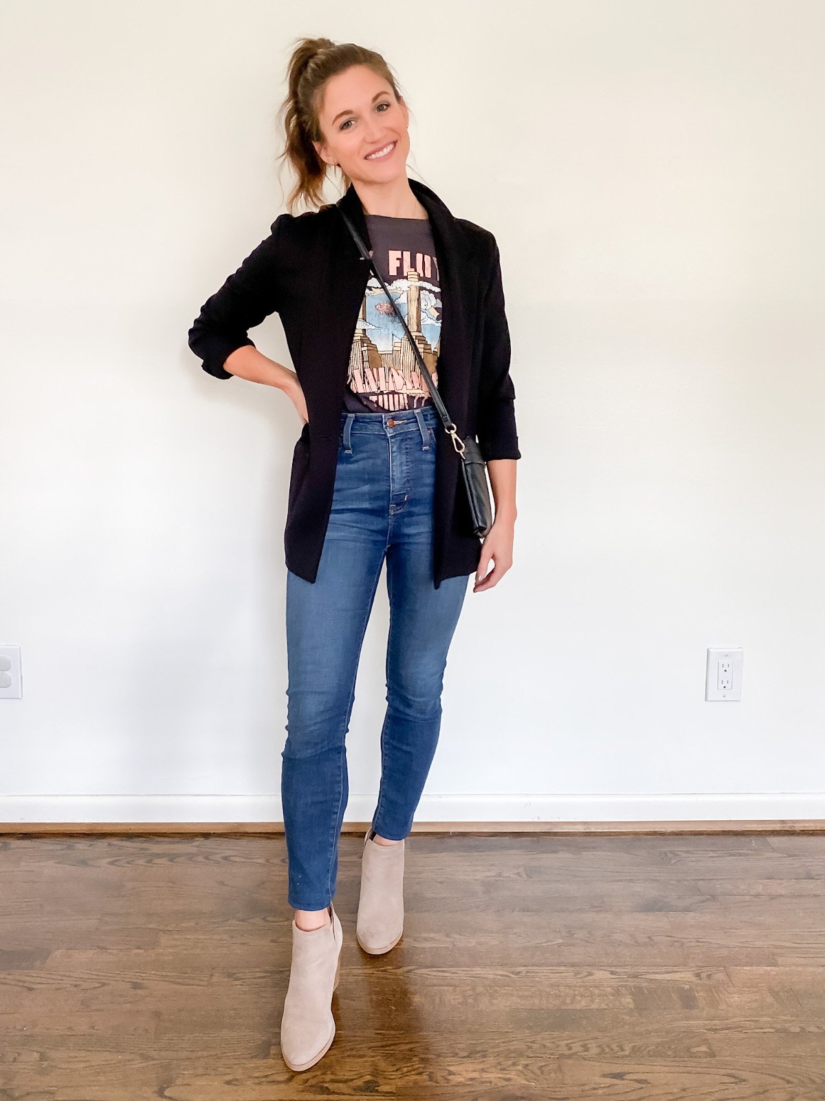 ashley wearing a black graphic tee, black blazer and mid-wash skinny jeans with taupe ankle boots