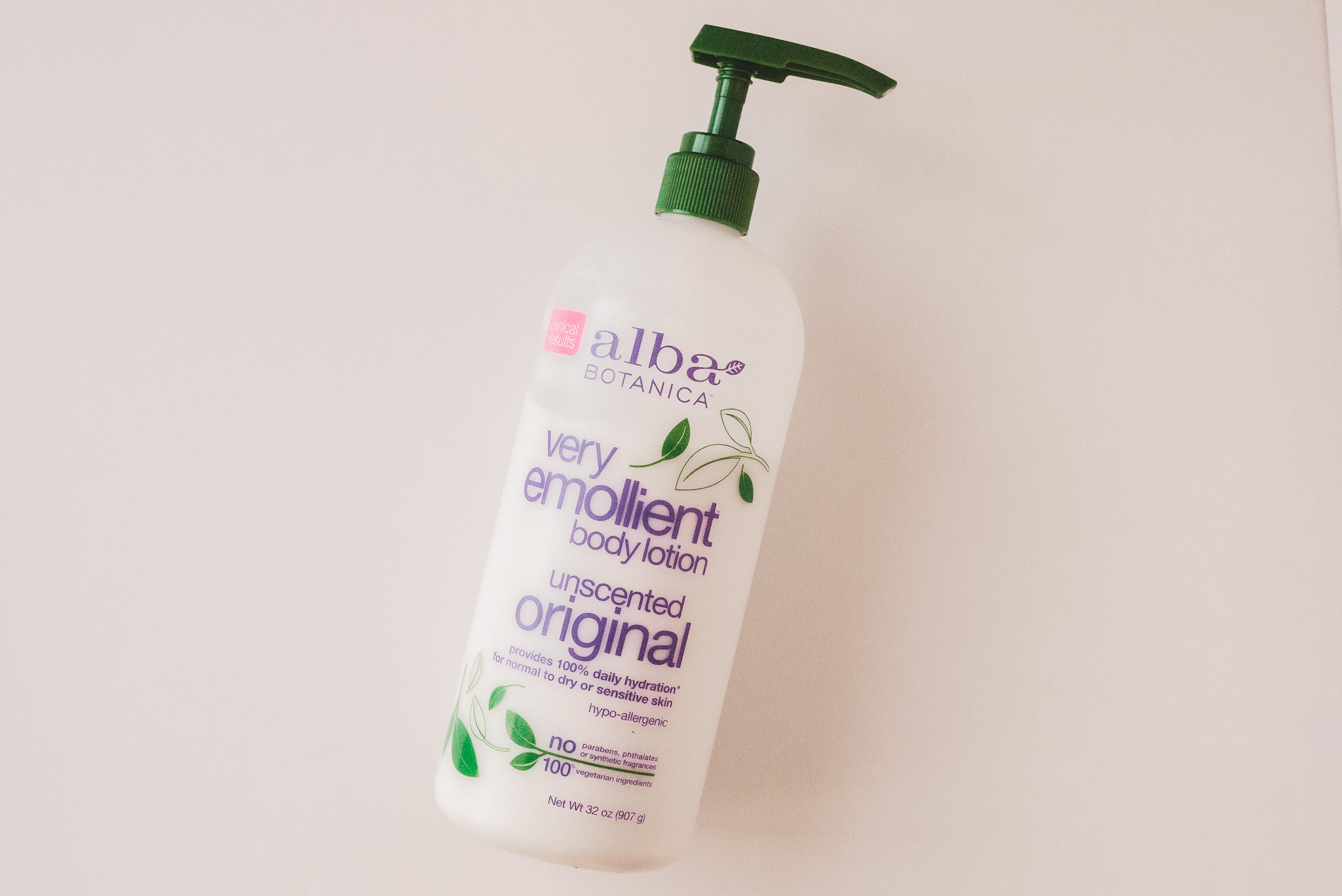 a clear botle of Alba Botanica Lotion on a white background