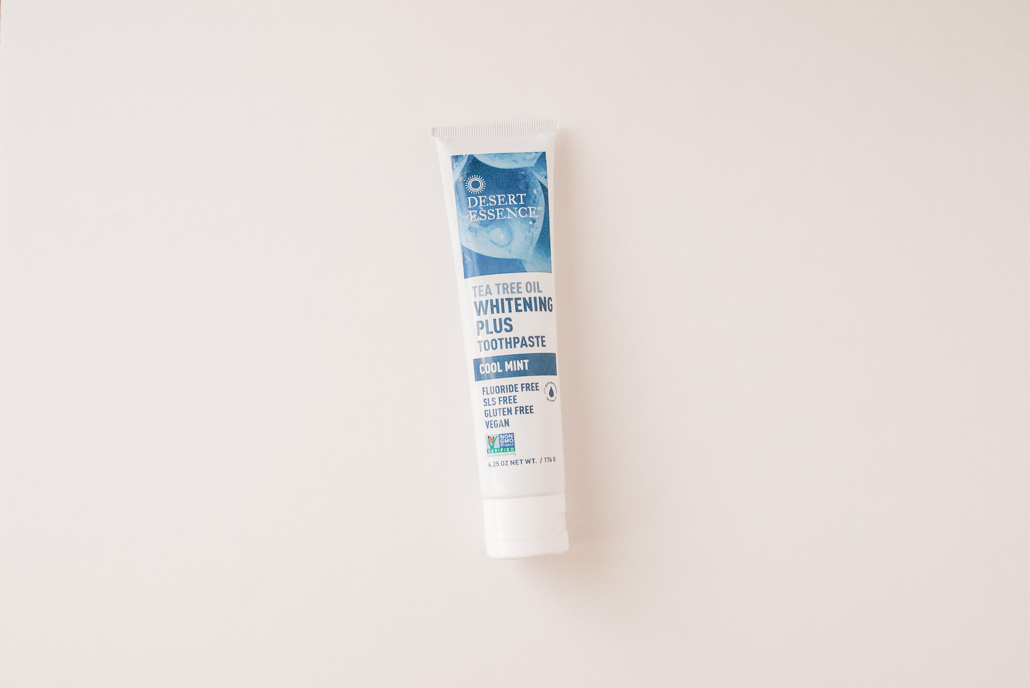 A white tube of Desert Essence Whitening Toothpaste on a white background