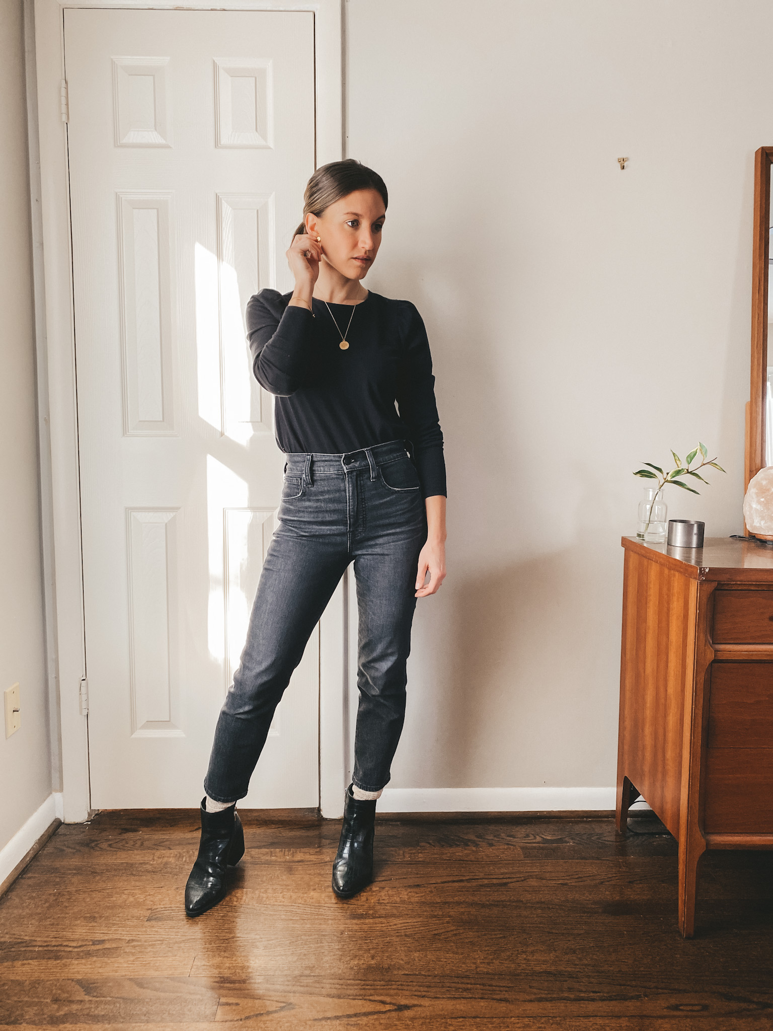 ashley wearing a black puff sleeve top from Madewell, Madewell washed black straight leg jeans and black boots from Target