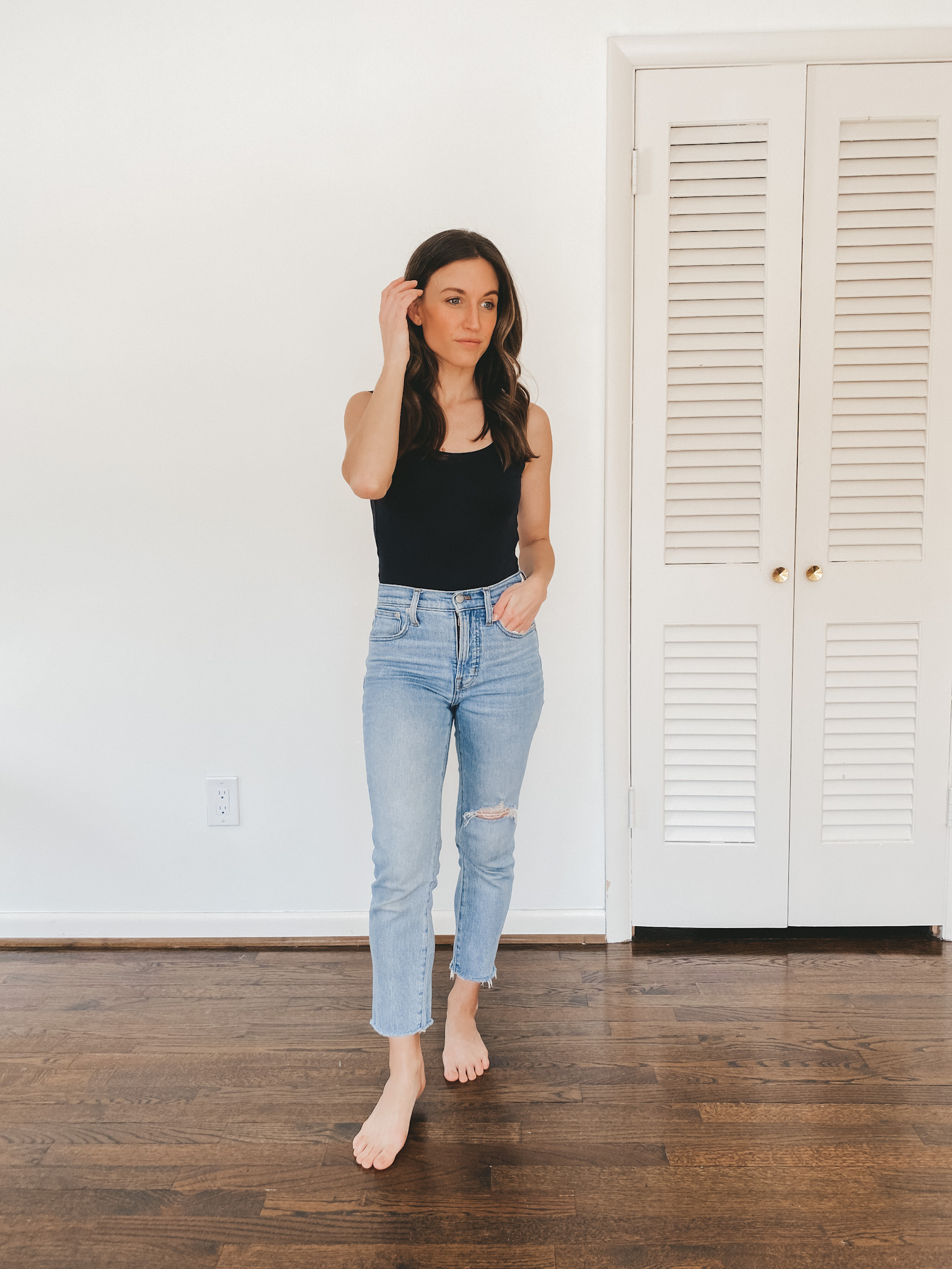 ashley wearing a black Everlane bodysuit and light wash Perfect Vintage Jeans from Madewell