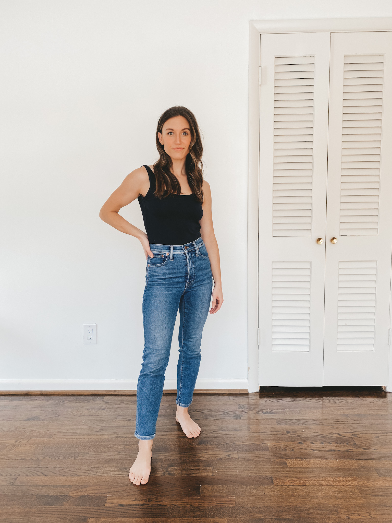 ashley wearing a black Everlane bodysuit and mid-wash Perfect Vintage Jeans from Madewell