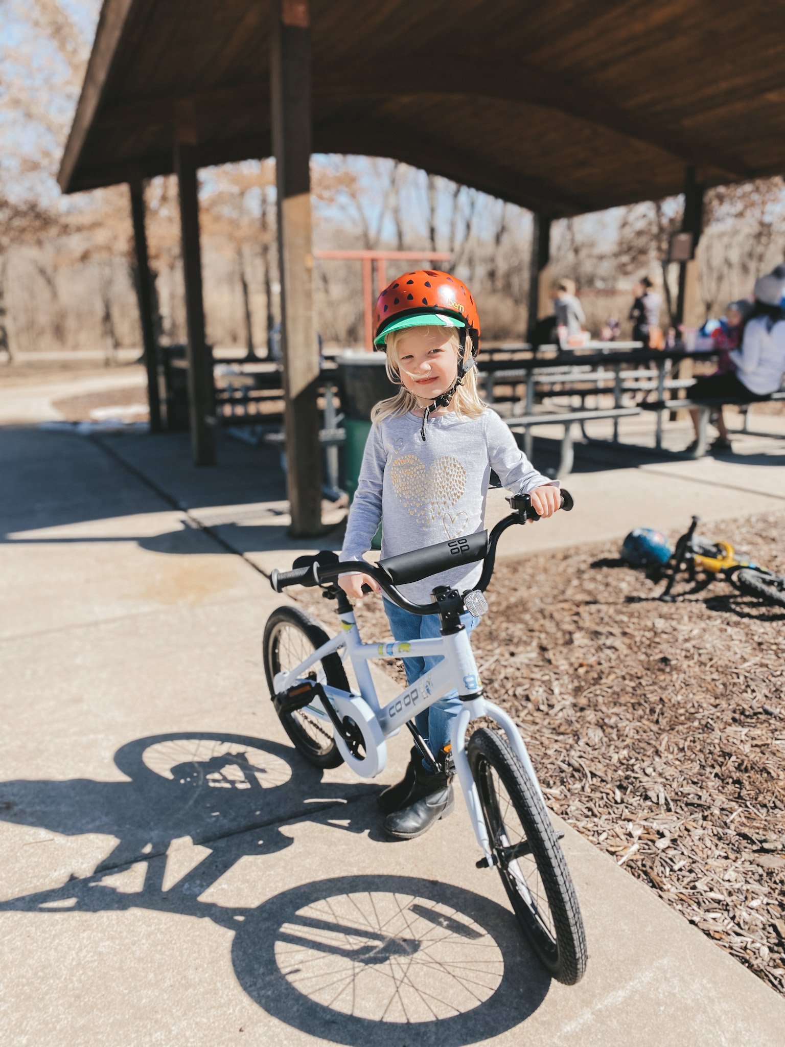 girl standing next to a bike at a park