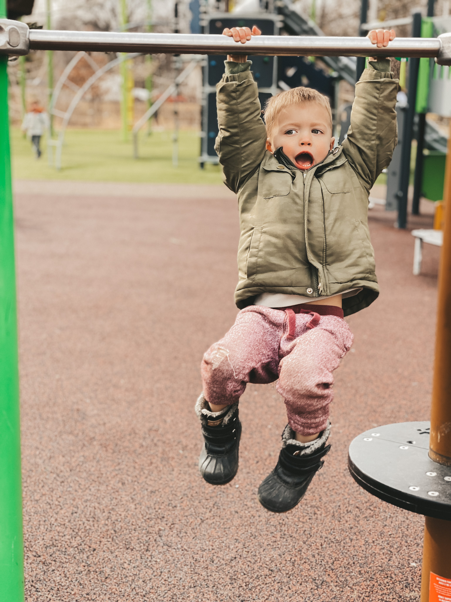 boy hanging from bar on playground