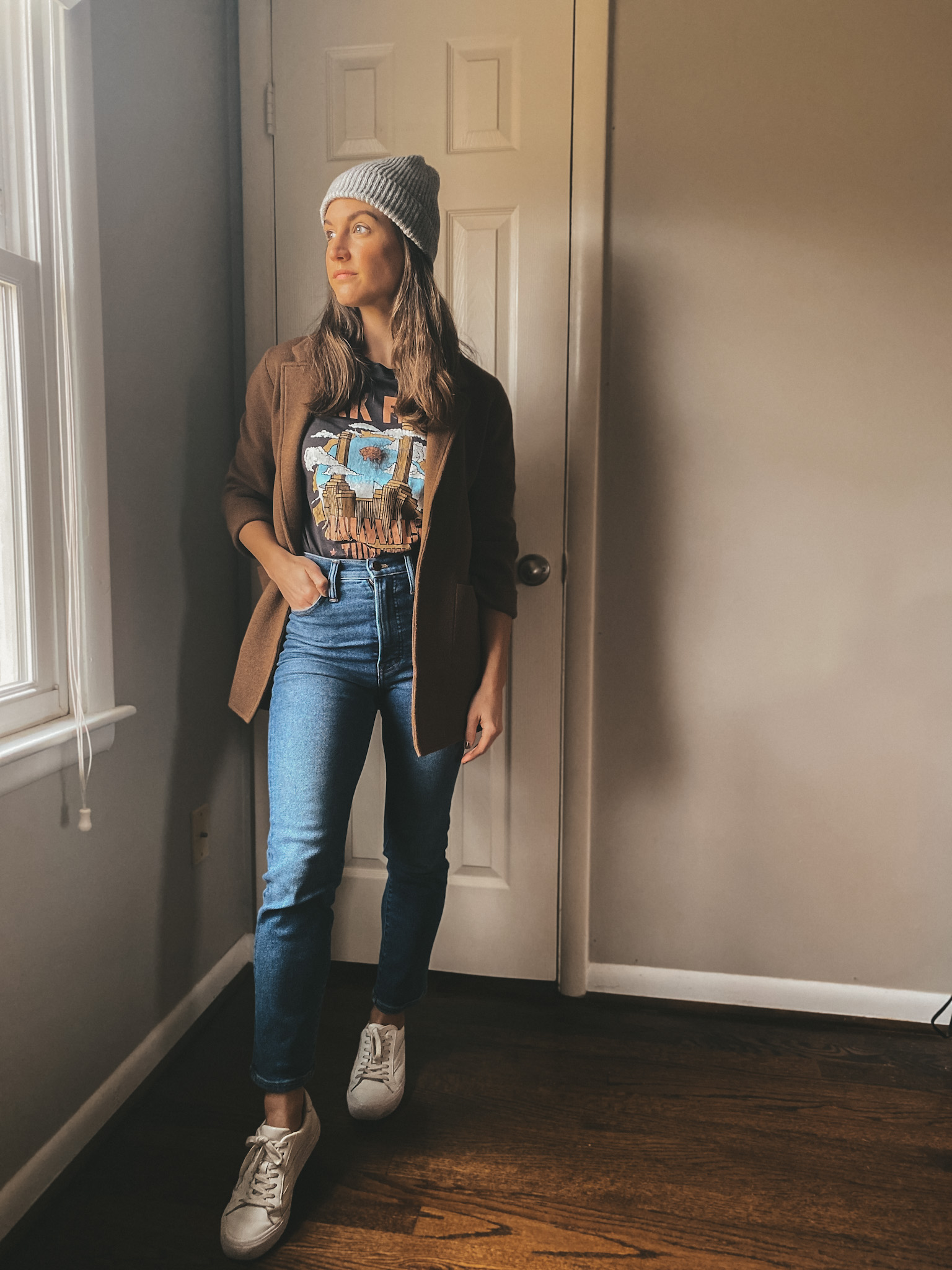 ashley wearing a black graphic tee, a brown sweater blazer from J.Crew, straight leg jeans from Madewell, a gray beanie from Target, white sneakers from Madewell