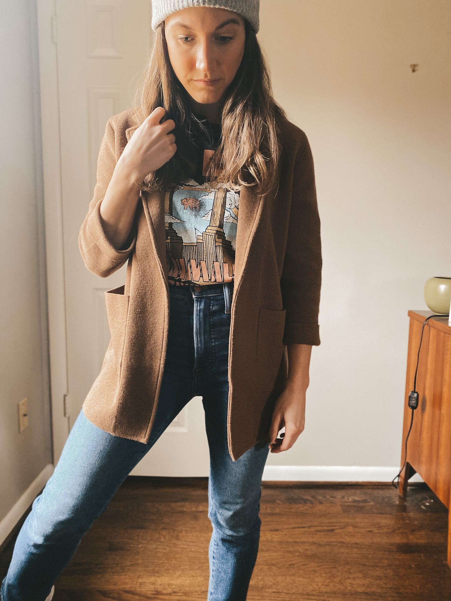 ashley wearing a black graphic tee, a brown sweater blazer from J.Crew, straight leg jeans from Madewell, a gray beanie from Target
