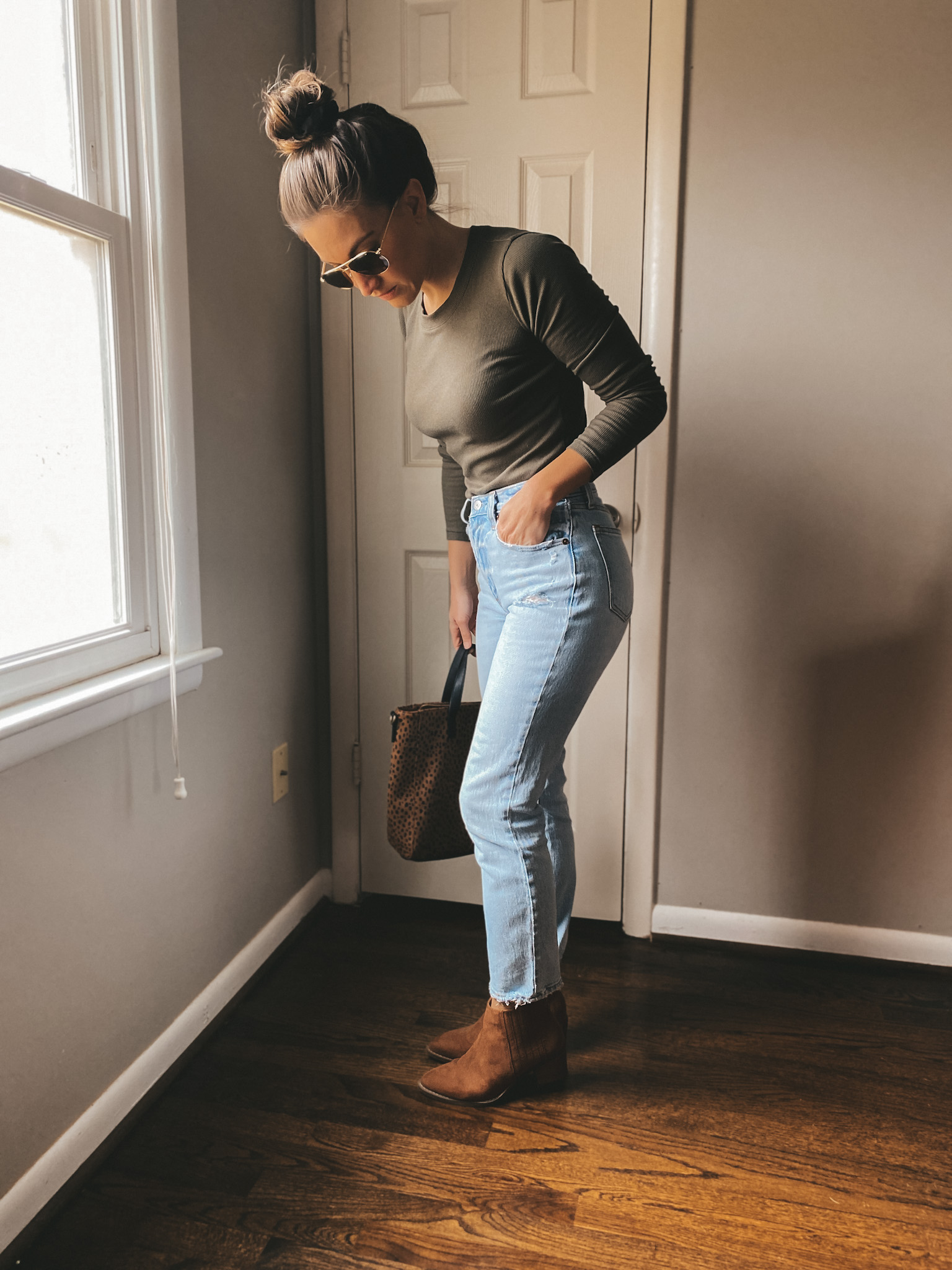 ashley wearing olive green long sleeved tee from Madewell, distressed light wash jeans from Madewell, cognac ankle boots from Target and sunglasses from AO