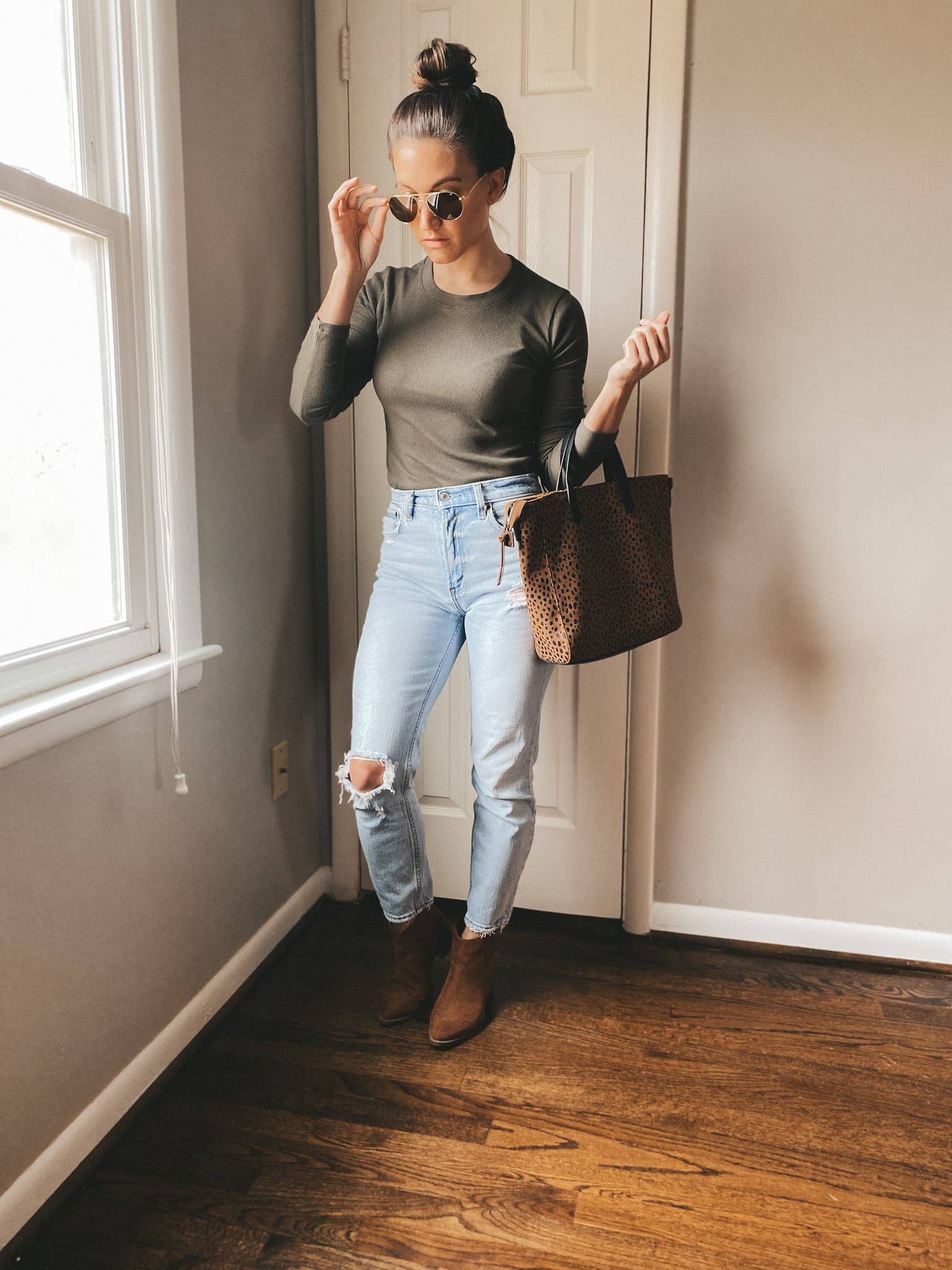 ashley wearing olive green long sleeved tee from Madewell, distressed light wash jeans from Madewell, cognac ankle boots from Target and sunglasses from AO