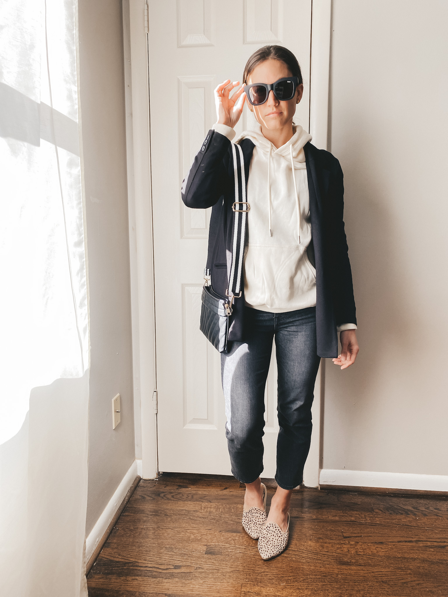 ashley wearing a cream hoodie from H&M, black blazer from Old Navy, Sunglasses from Quay, Jeans from Madewell, Leopard Mules from Target