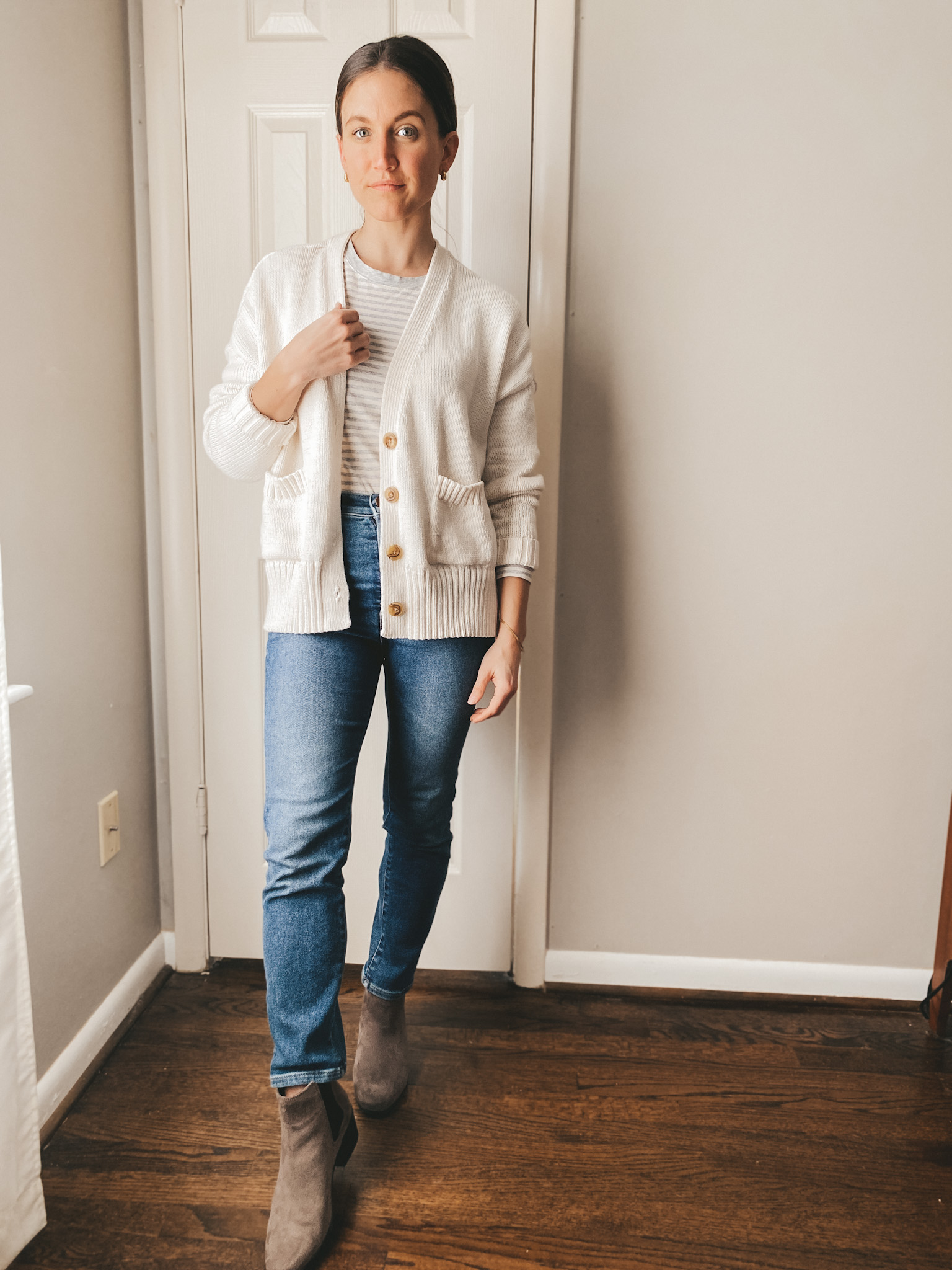 ashley wearing a gray and cream striped tee from Loft, a cream colored button front cardigan from Target, jeans from Madewell and gray chelsea boots from Target