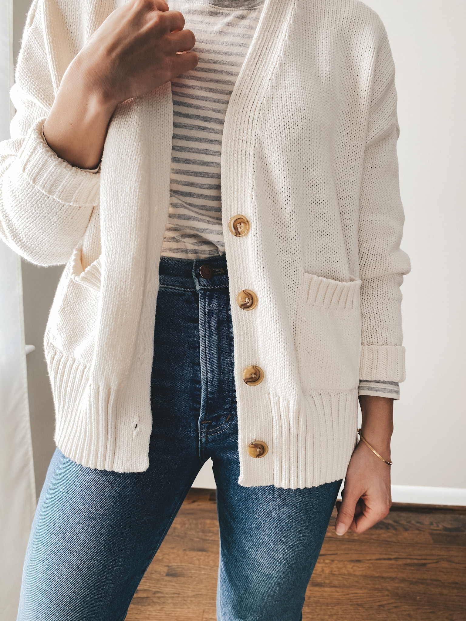 ashley wearing a gray and cream striped tee from Loft, a cream colored button front cardigan from Target, jeans from Madewell