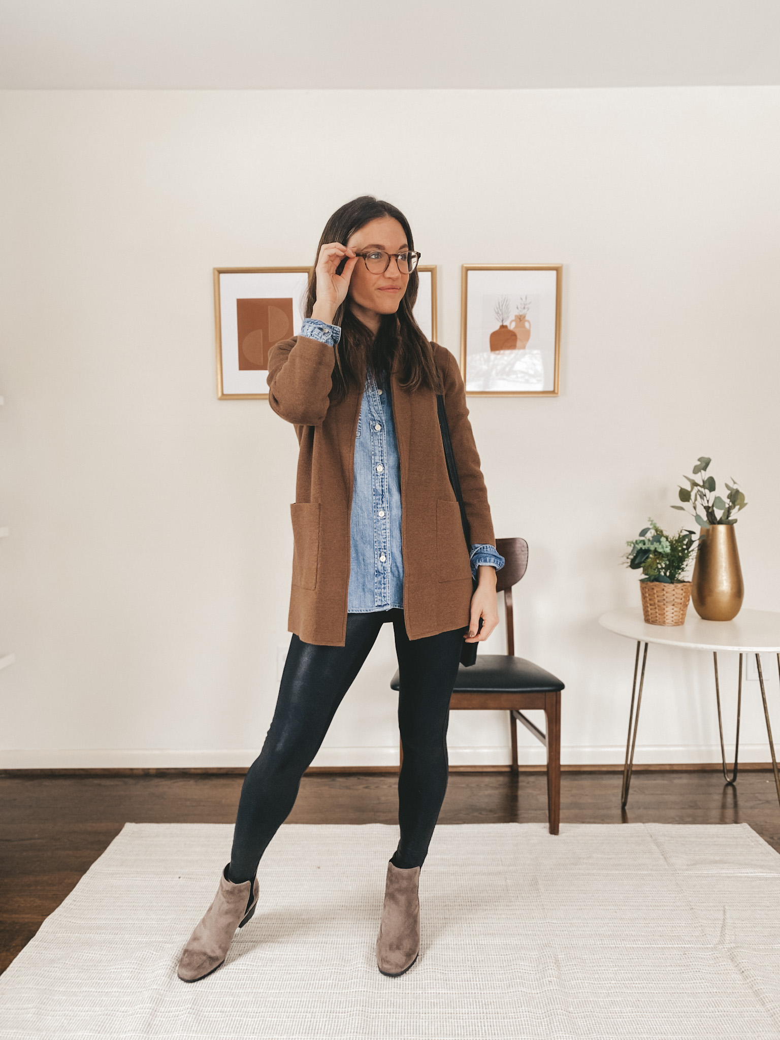 ashley wearing glasses, a chambray button down, brown sweater blazer, faux legggings, and brown chelsea boots