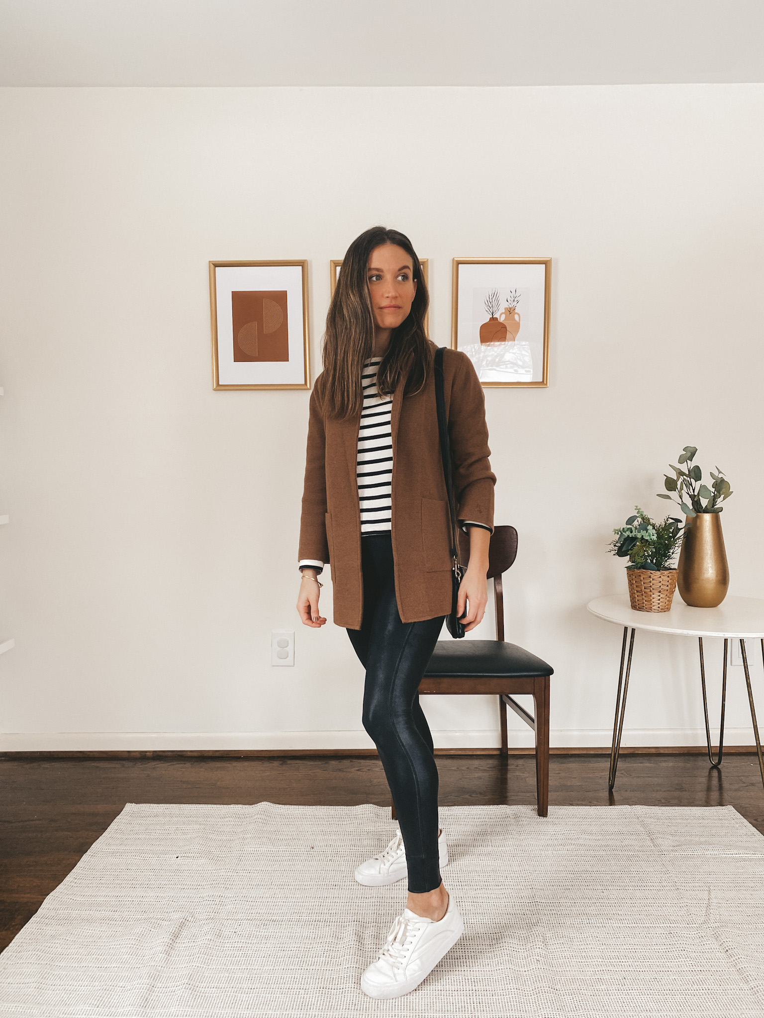 ashley wearing a black and white striped shirt, a brown sweater blazer, faux leather leggings, and white sneakers