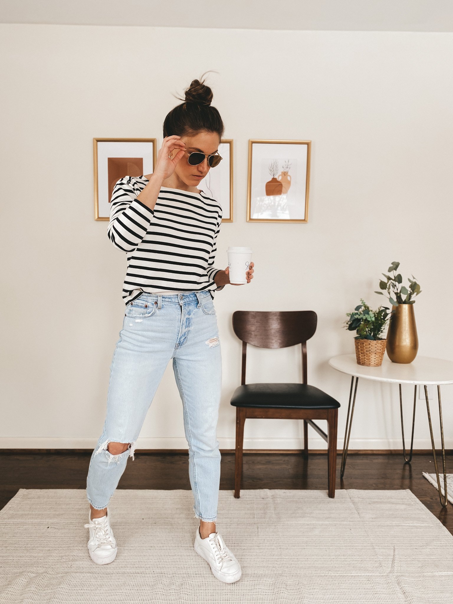 ashley wearing a striped stop from Everlane, light wash distressed jeans from Abercrombie, white sneakers from Madewell, and aviators