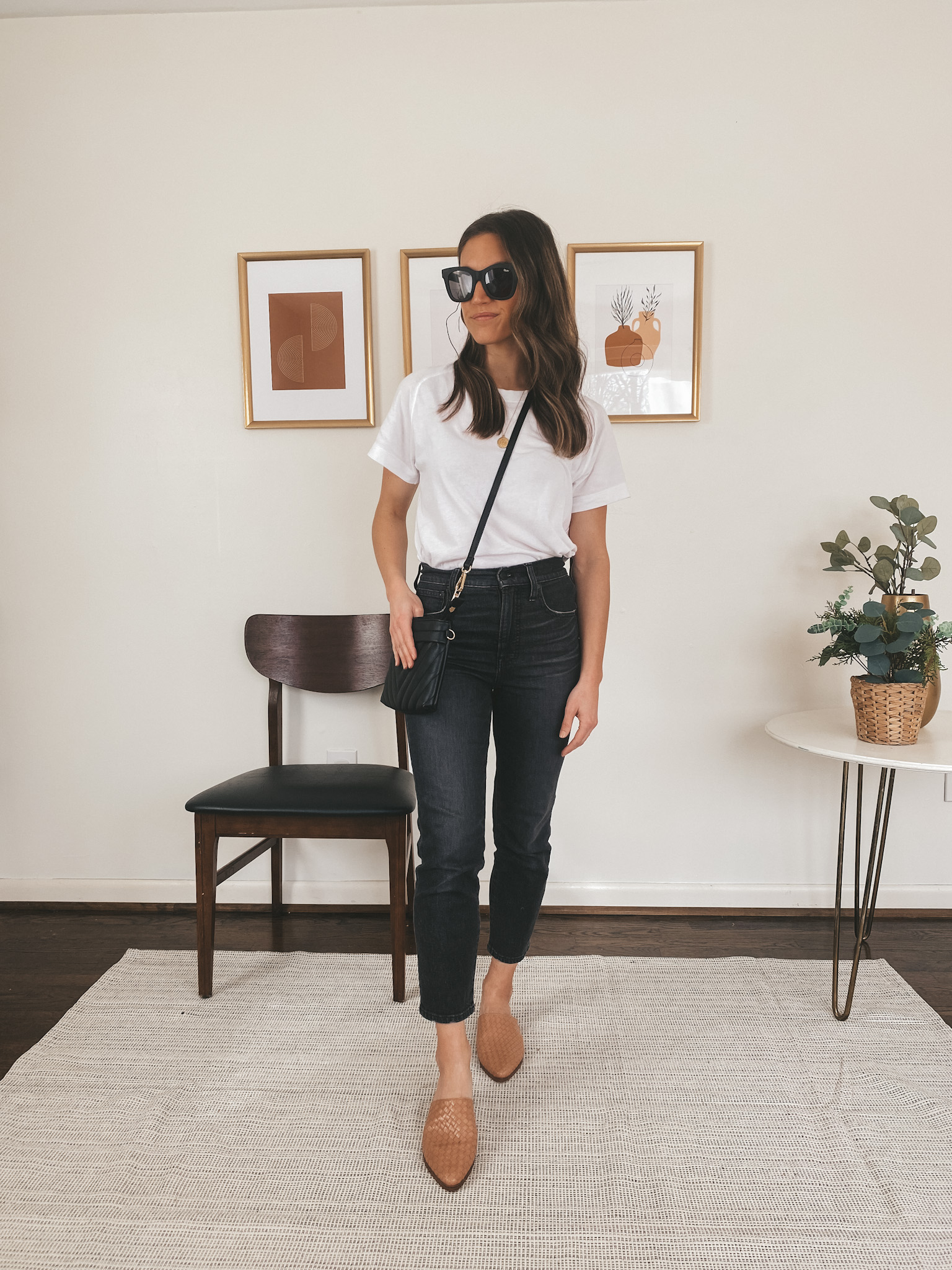 ashley wearing an Everlane white tee, Madewell washed black Perfect Vintage Jeans, Marc Fisher woven mules, a black quilted crossbody bag, and Quay black square frame sunglasses