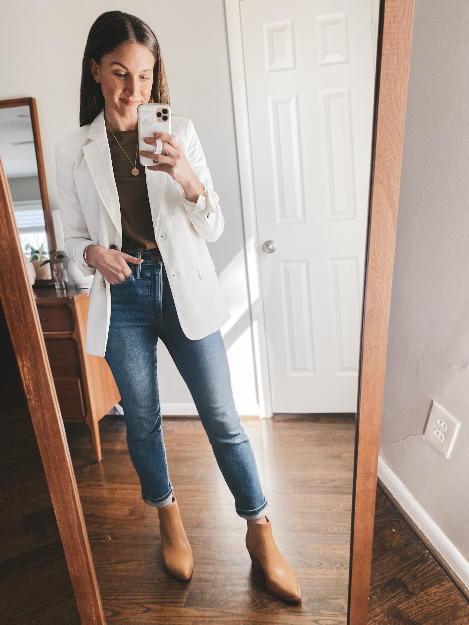 a mirror selfie; ashley wearing a Walmart white blazer, a brown Everlane tee, Madewell Perfect Vintage Jeans, and Target ankle boots