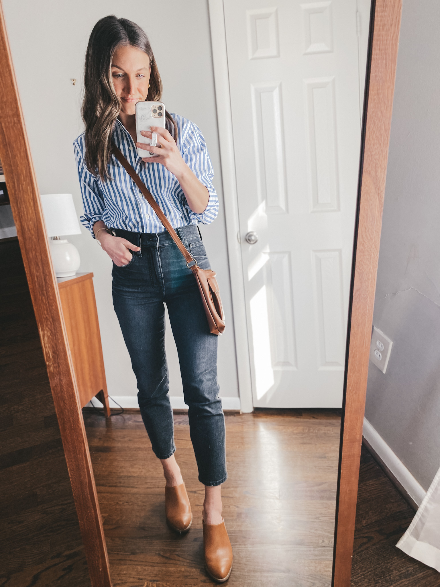 a mirror selfie; ashley wearing a white and blue striped button down from Walmart, Madewell washed black Perfect Vintage Jeans, Old Navy heeled mules, and a Target brown crossbody bag