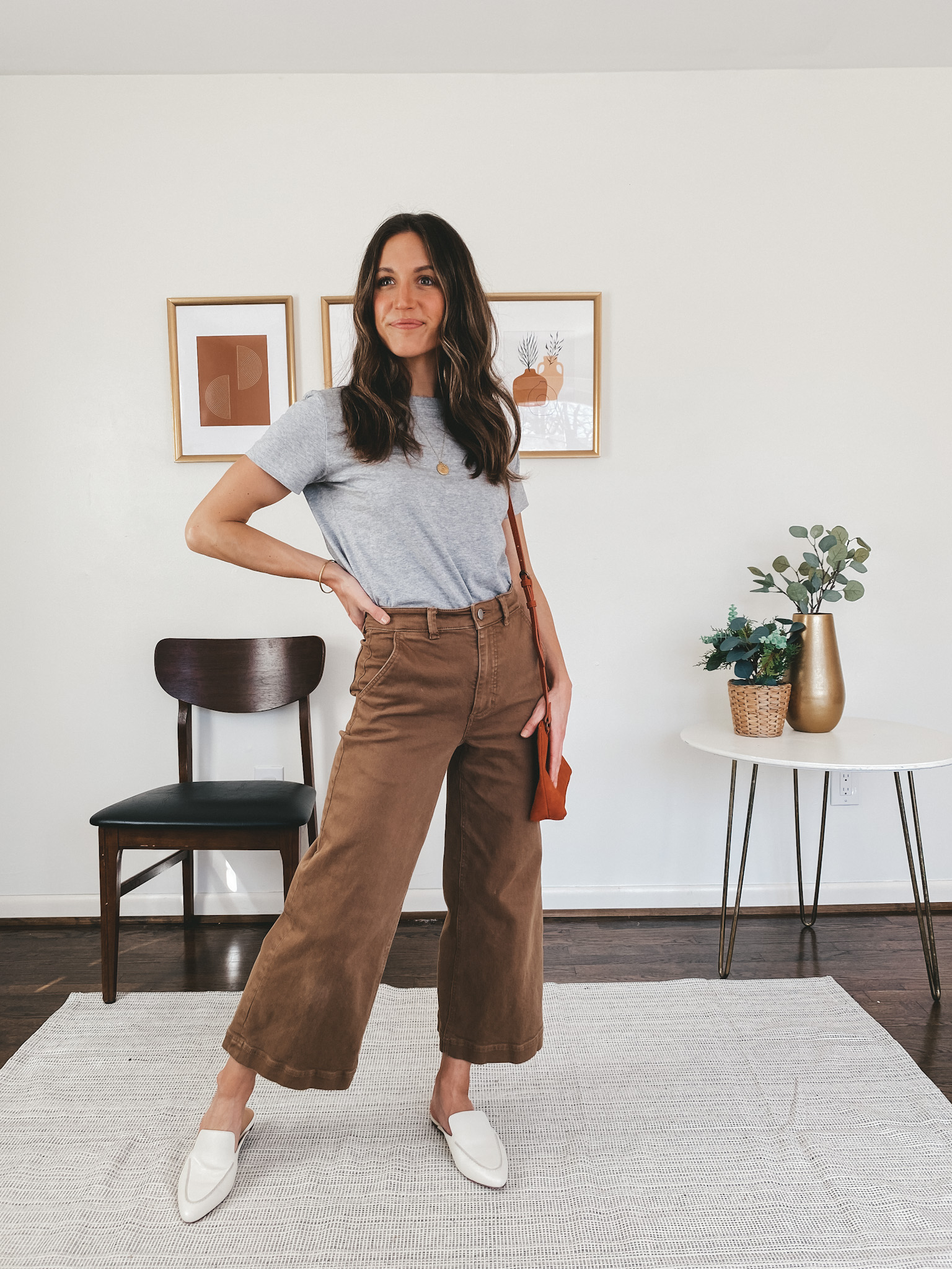 ashley wearing an Everlane gray tee, Everlane wide leg pants in ochre, Madewell white mules, and a Target rust colored crossbody bag