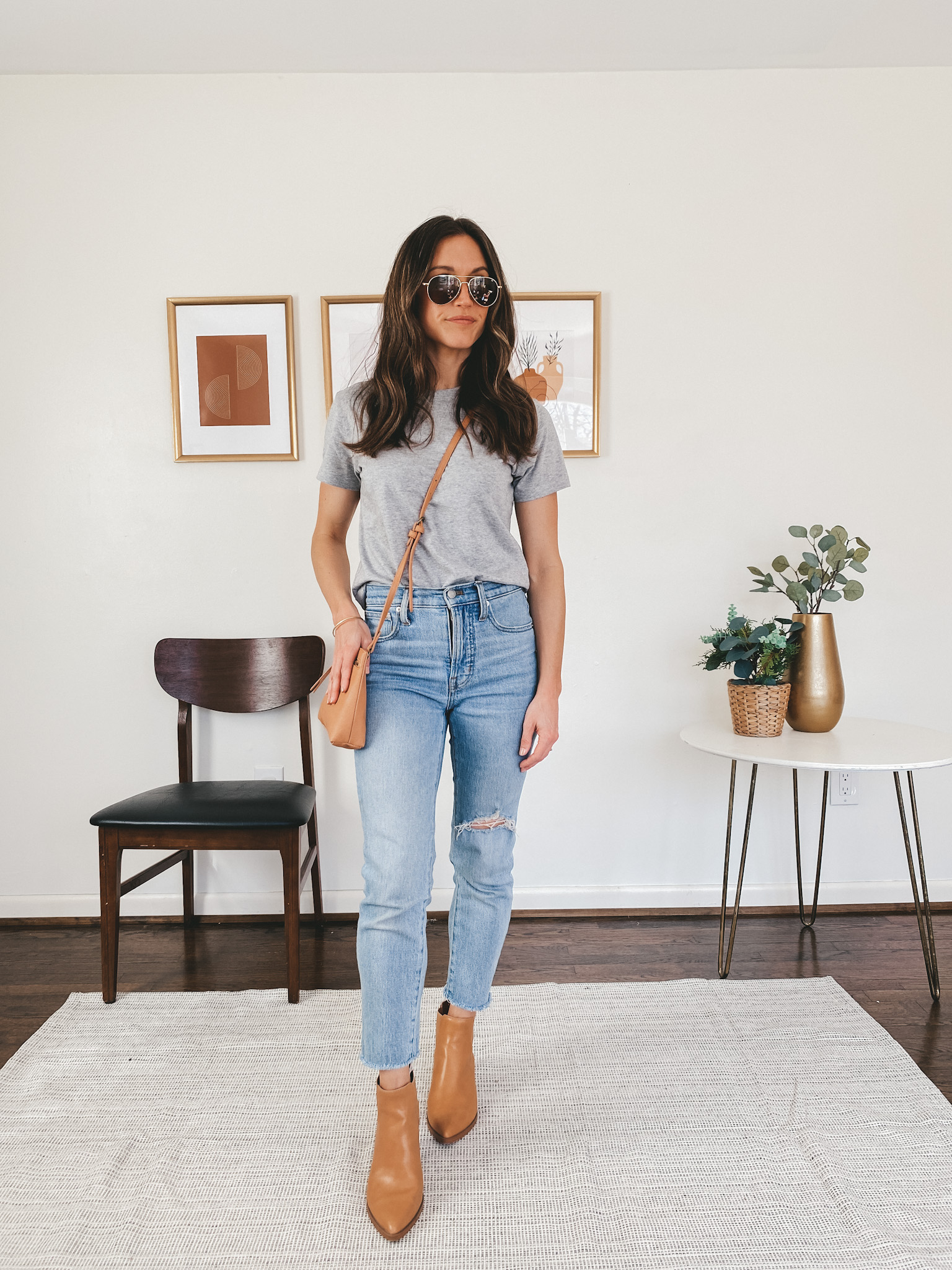 ashley wearing an Everlane gray tee, Madewell Perfect Vintage Jeans, Target camel ankle booties AO pilot sunglasses and a camel colored crossbody bag from Target