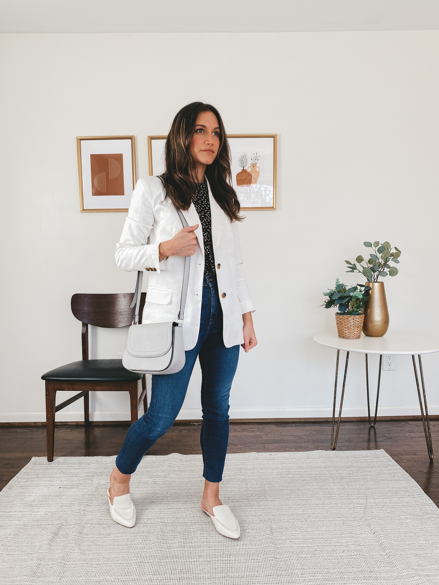 ashley wearing a Madewell puff sleeve blouse in black with a small flower pattern, a Walmart Free Assembly white blazer, Madewell skinny jeans, Madewell white mules, and a gray crossbody bag
