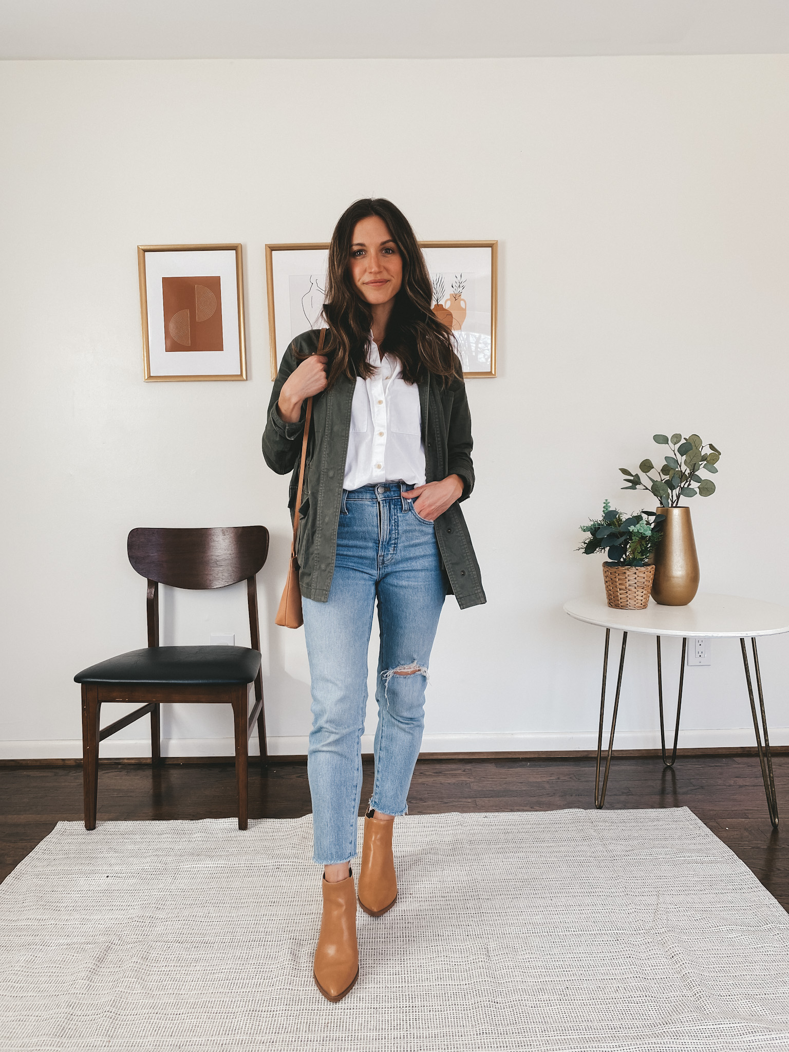 ashley wearing a Madewell white button down, Target green utility jacket, Madewell Perfect Vintage Jeans, and Target camel booties carrying a camel colored crossbody bag