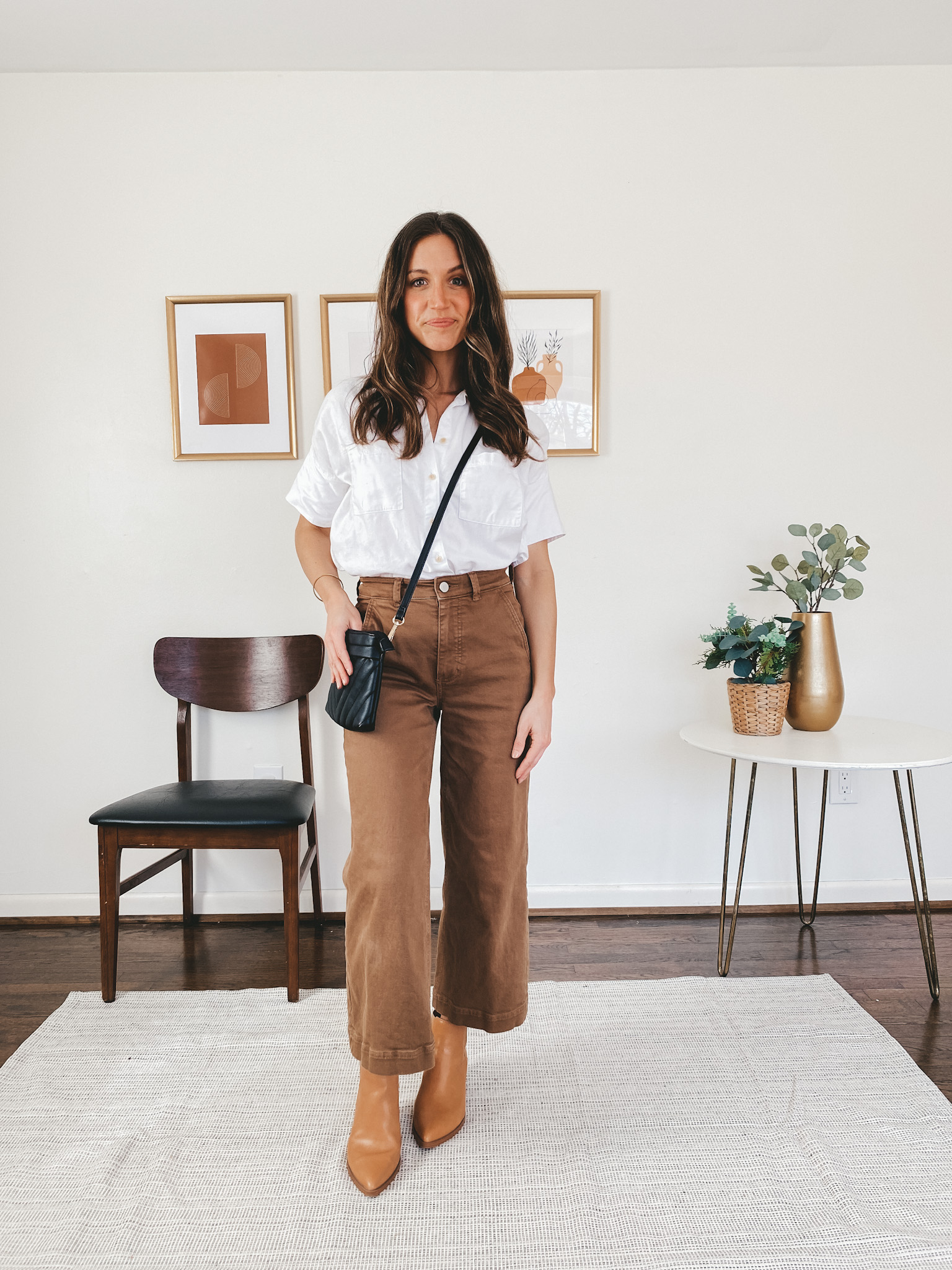 ashley wearing a Madewell white button down, Everlane wide leg pants in ochre, Target camel colored ankle boots, and a black quilted crossbody purse