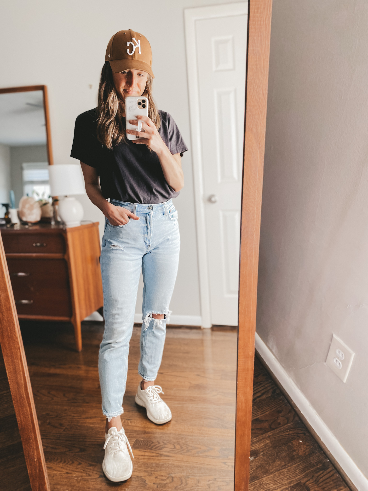 ashley wearing an Everlane black tee, Abercrombie mom jeans, Allbirds wool runners in white, and a brown KC baseball hat