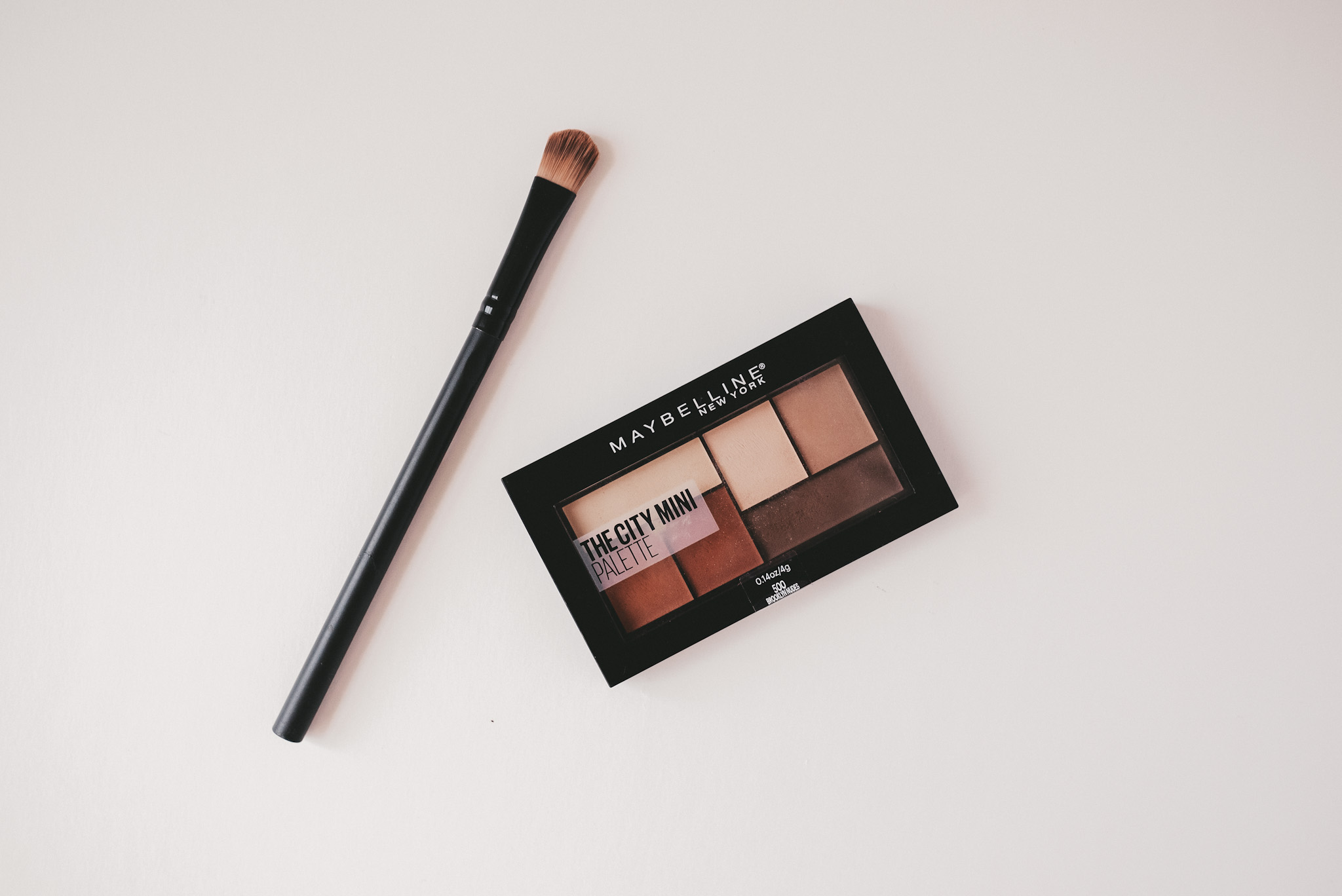 a white background; Maybelline eye shadow palette and eye shadow brush