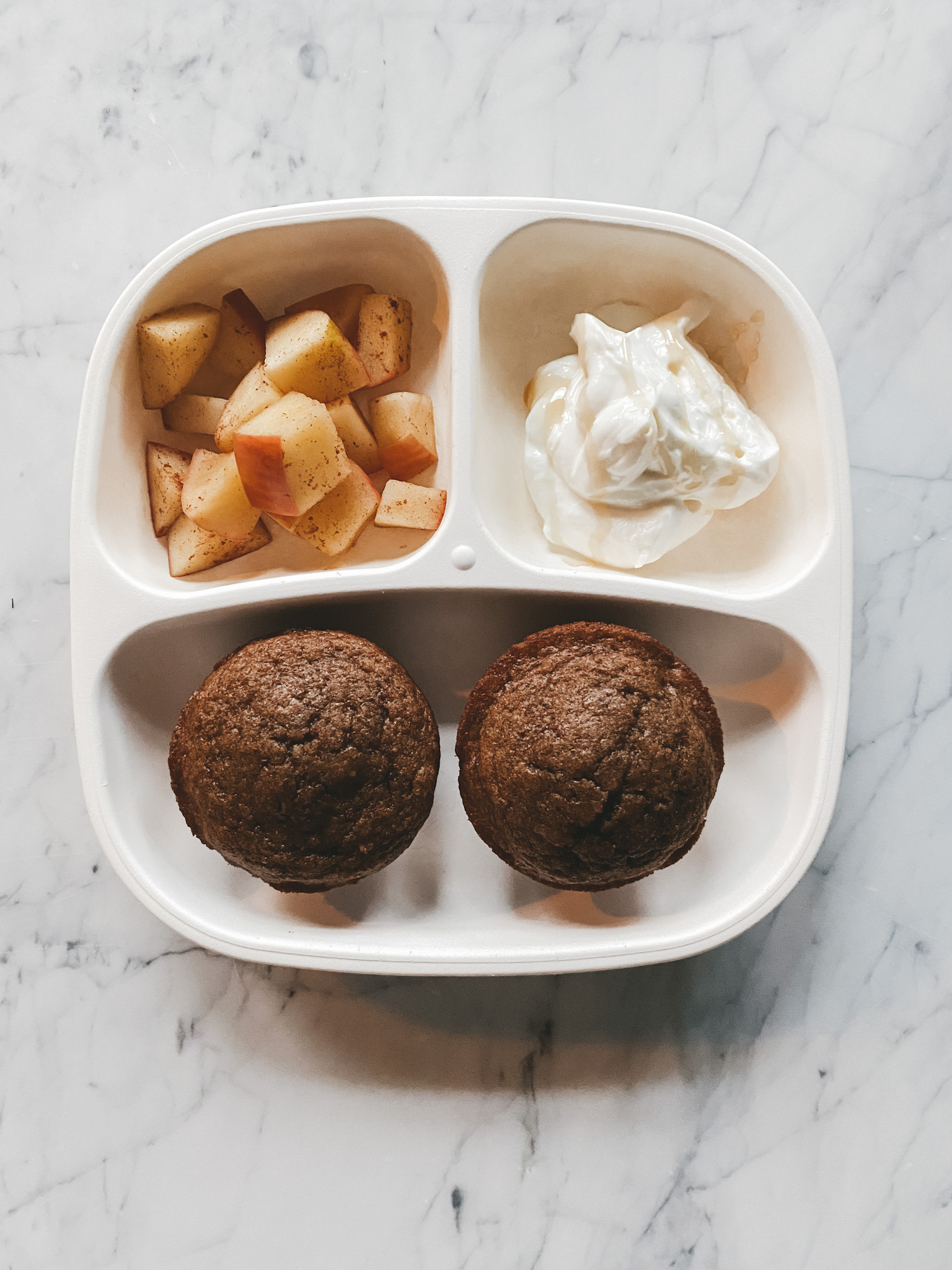 a white toddler plate with muffins, greek yogurt and cinnamon apples