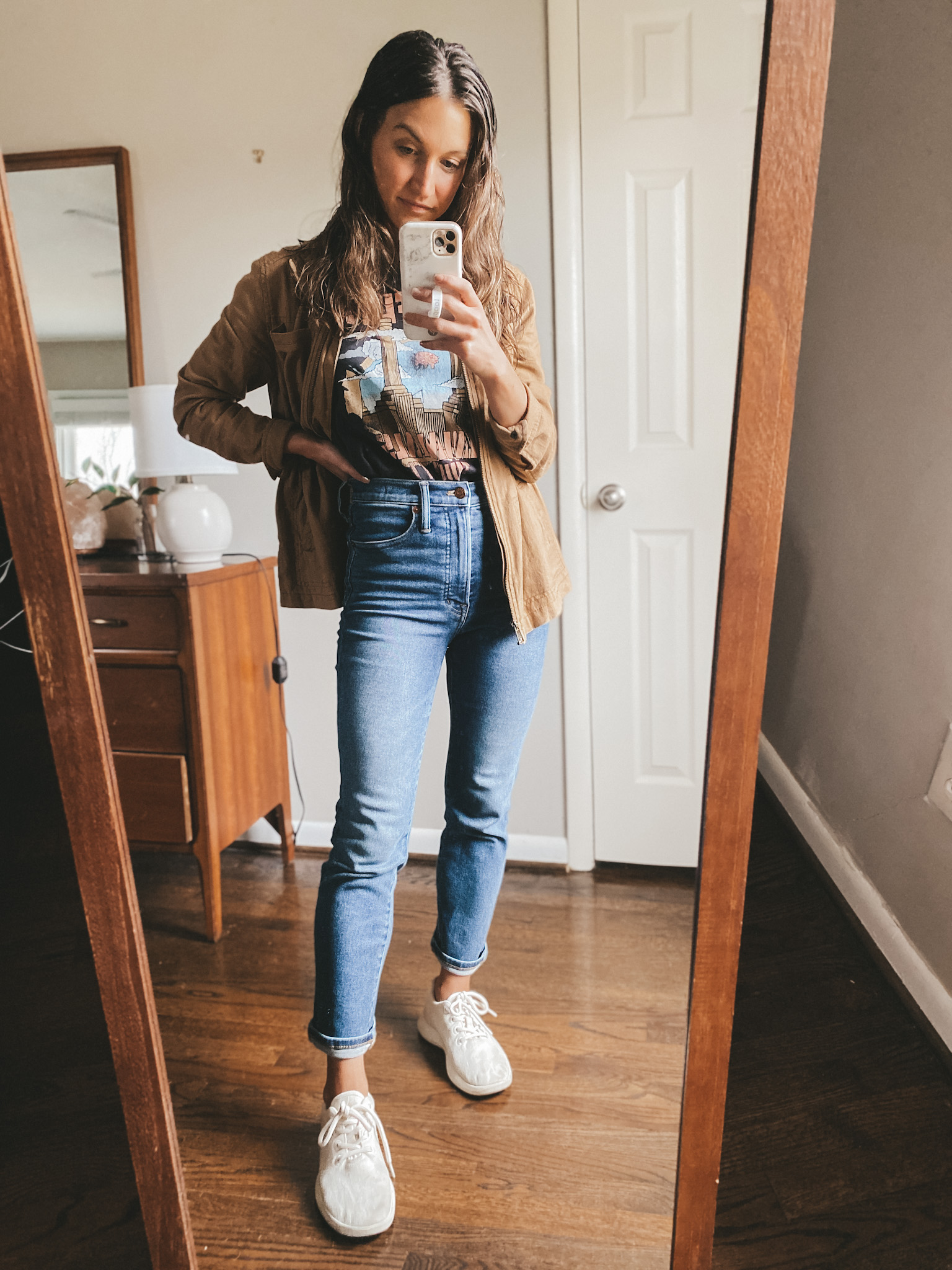 ashley wearing a black graphic tee from H&M, a tan utility jacket from Old Navy, Madewell Denim and Allbirds wool runners
