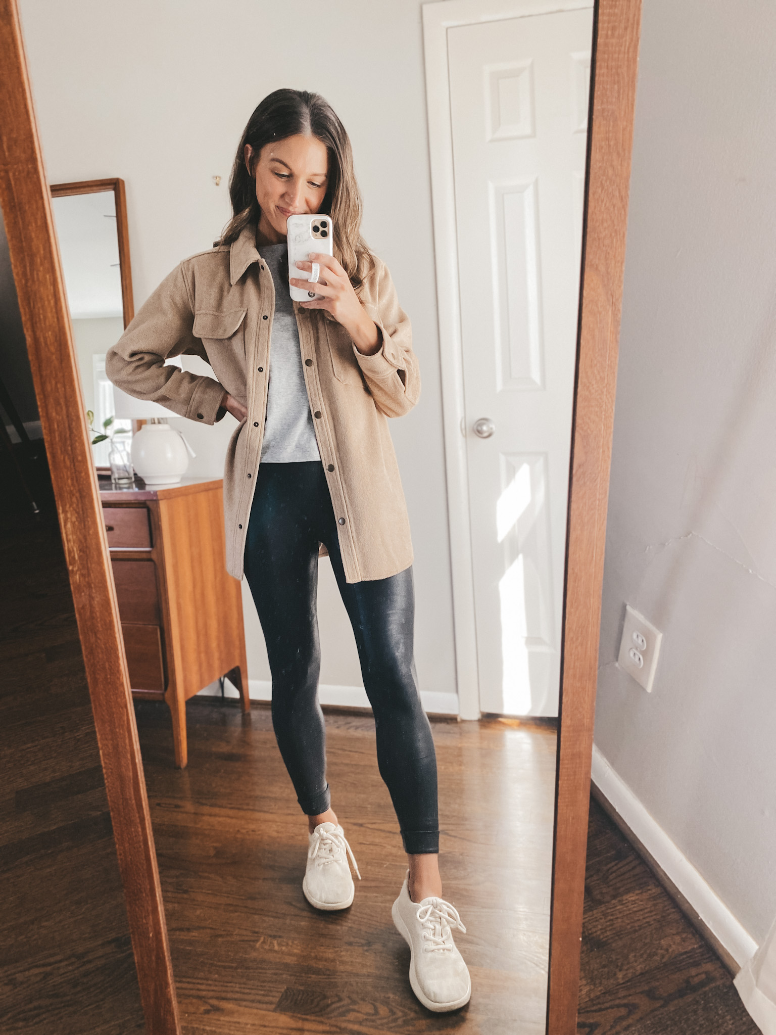 ashley wearing a gray Everlane tee, a tan shacket from Old Navy, Spanx faux leather leggings and Allbirds wool runners in white