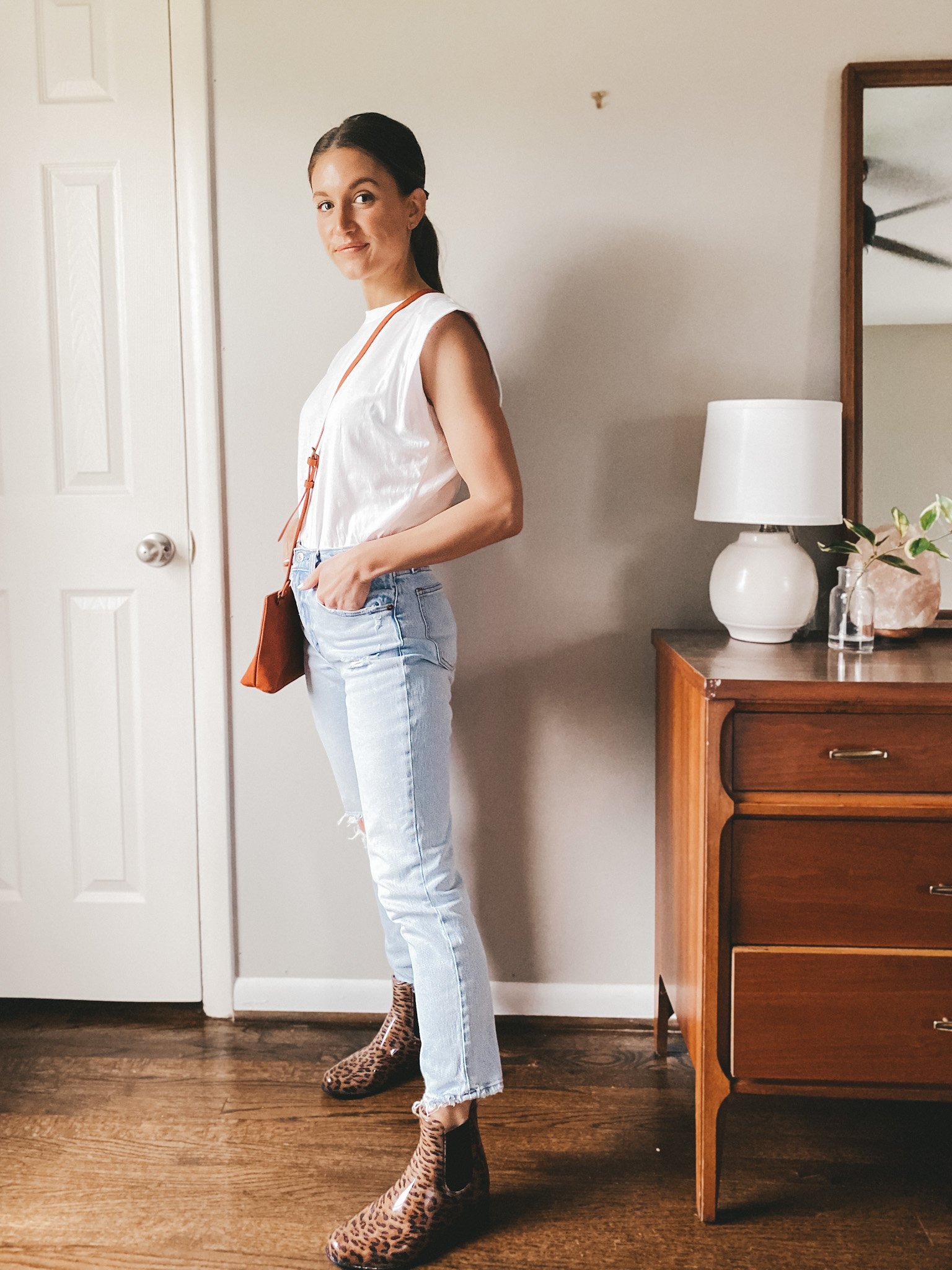 ashley wearing a white muscle tee, distressed mom jeans and leopard print rain boots