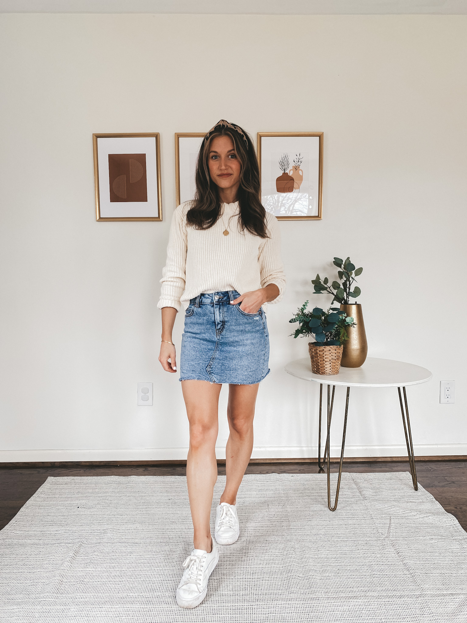 ashley wearing a cream sweater from Walmart, a denim skirt from Target, white sneakers from Madewell and a leopard knotted headband from J.Crew