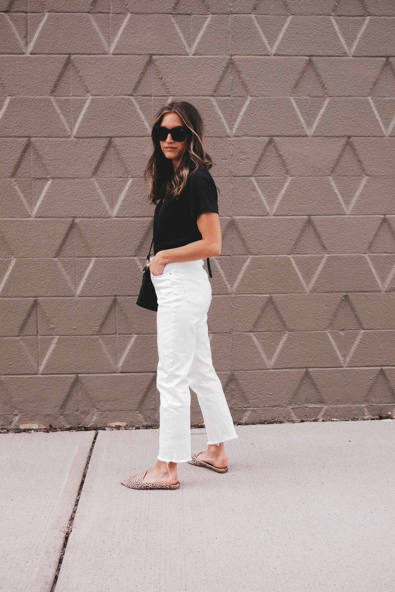 ashley wearing an Everlane black tee, white Everlane straight leg jeans, and Target leopard mules