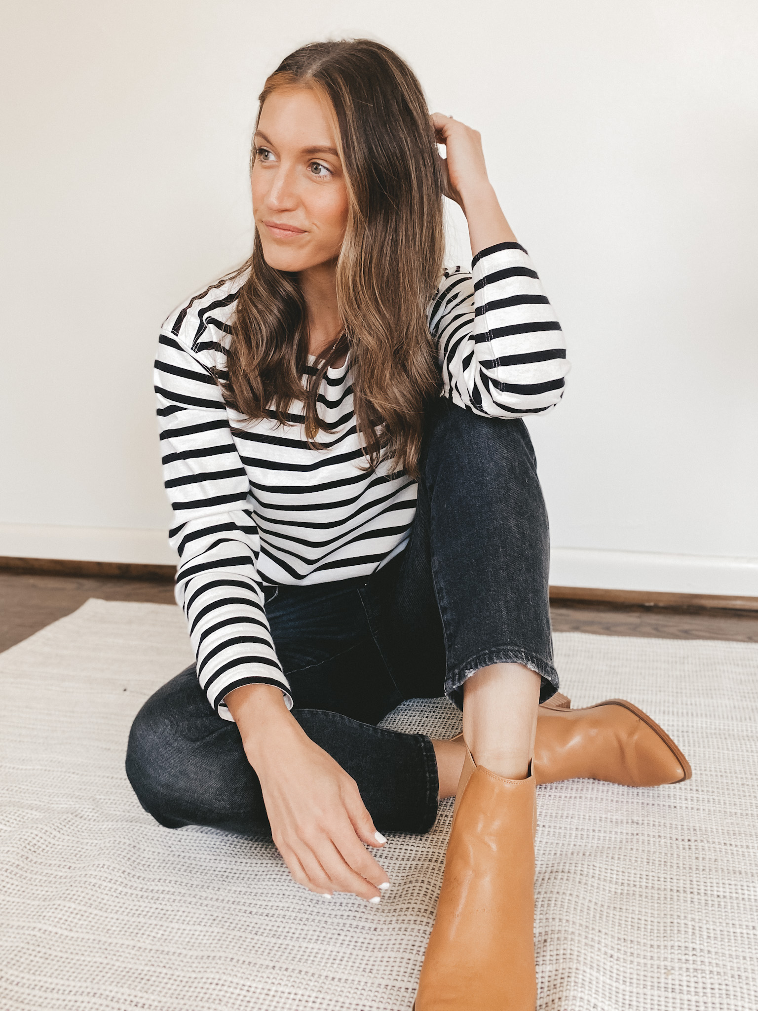Ashley wearing an Everlane striped top, washed black Madewell Perfect Vintage Jeans, and camel ankle booties from Target