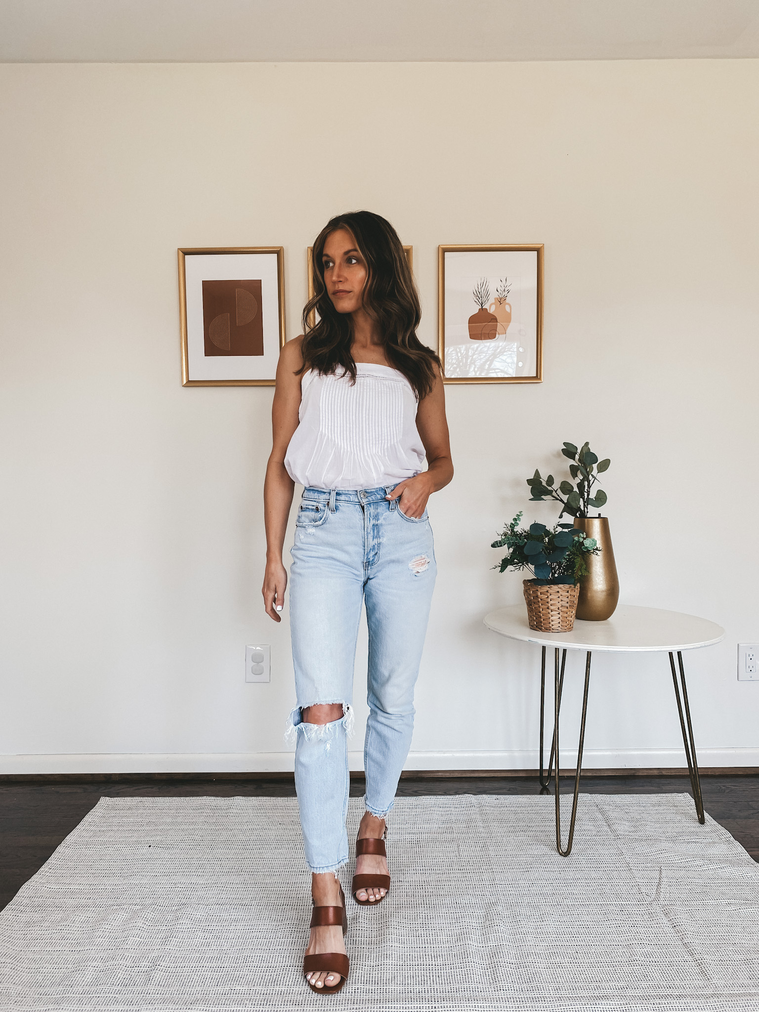 ashley wearing a white eyelet tank, distressed mom jeans, and block heeled brown sandals