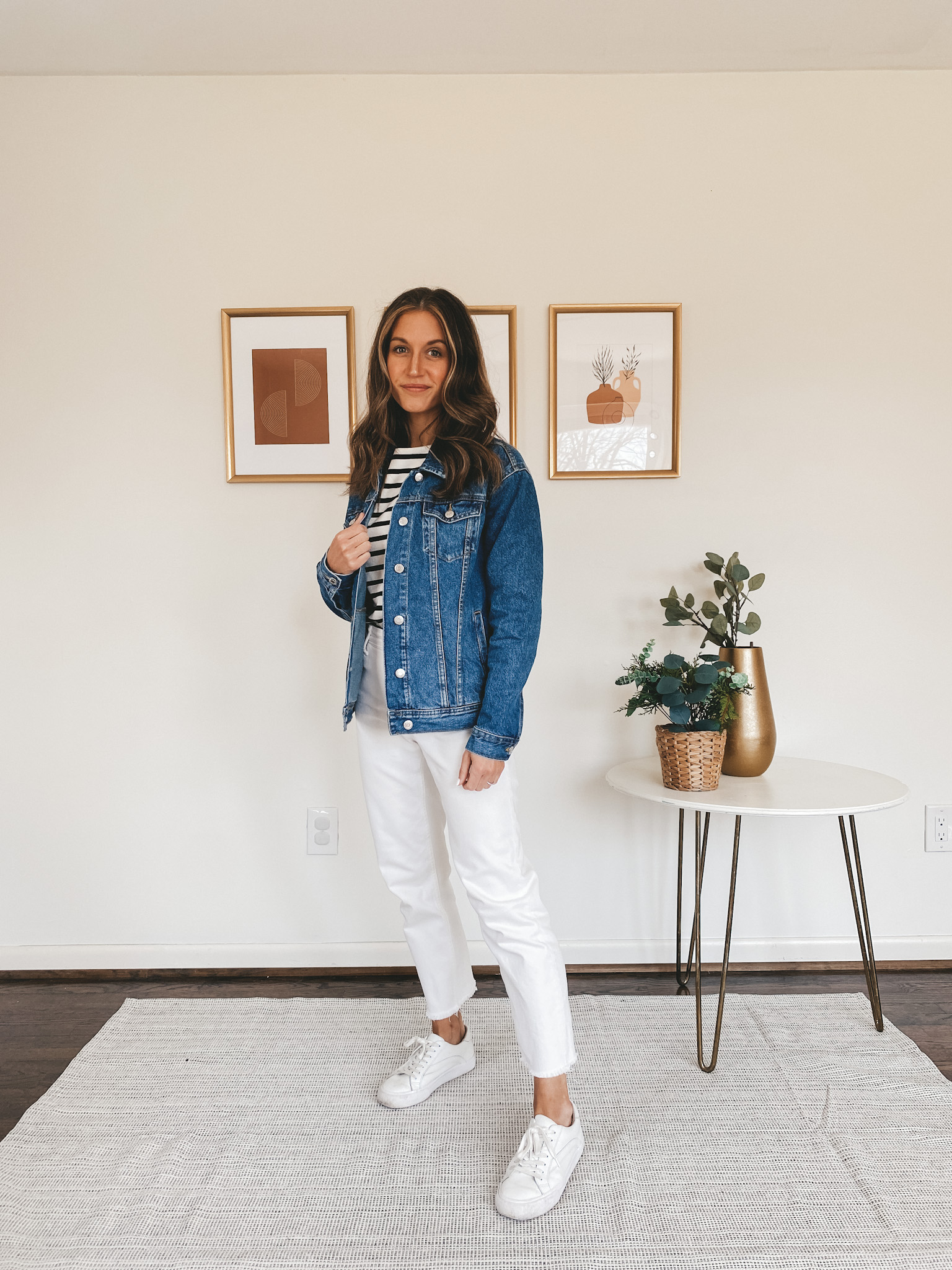 ashley wearing a breton top, denim jacket, white jeans, and white sneakers