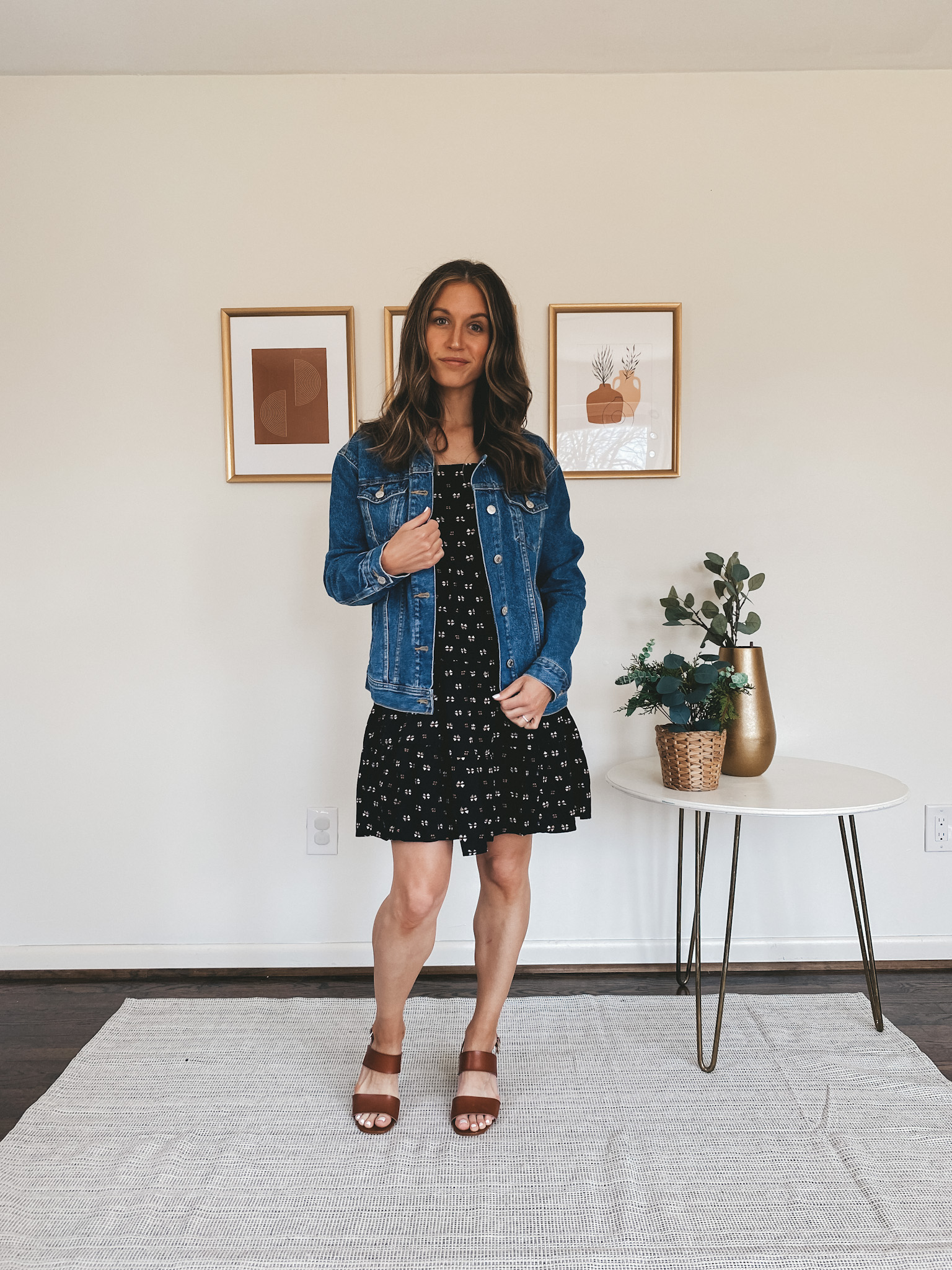 ashley wearing a black mini tiered dress, denim jacket, and brown block heeled sandals