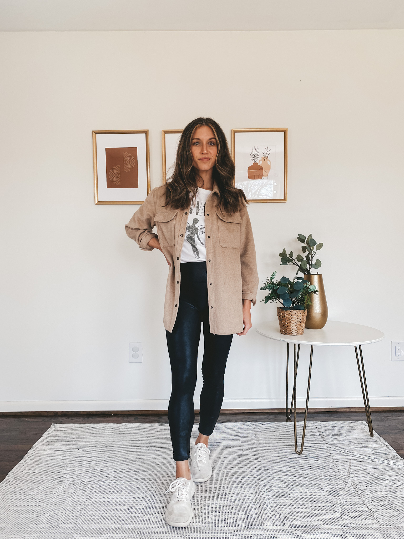 ashley wearing a white graphic tee, tan shacket, faux leather leggings, and white sneakers