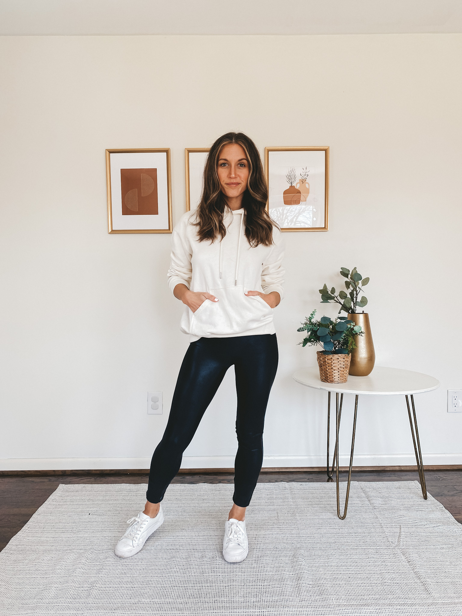 ashley wearing faux leather leggings, a cream hoodie, and white runners