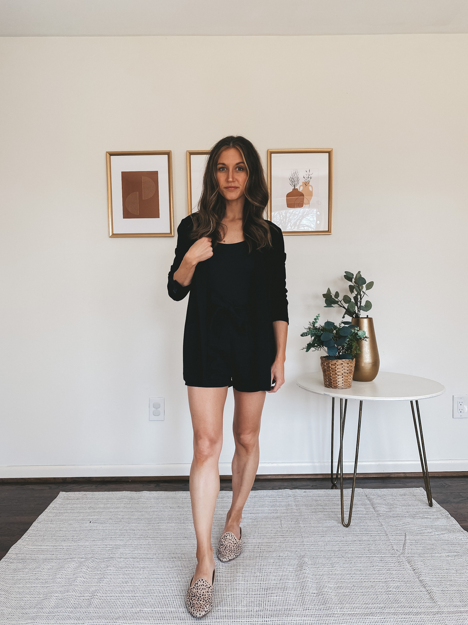 ashley wearing a black bodysuit, black blazer, and black paperbag shorts with leopard mules