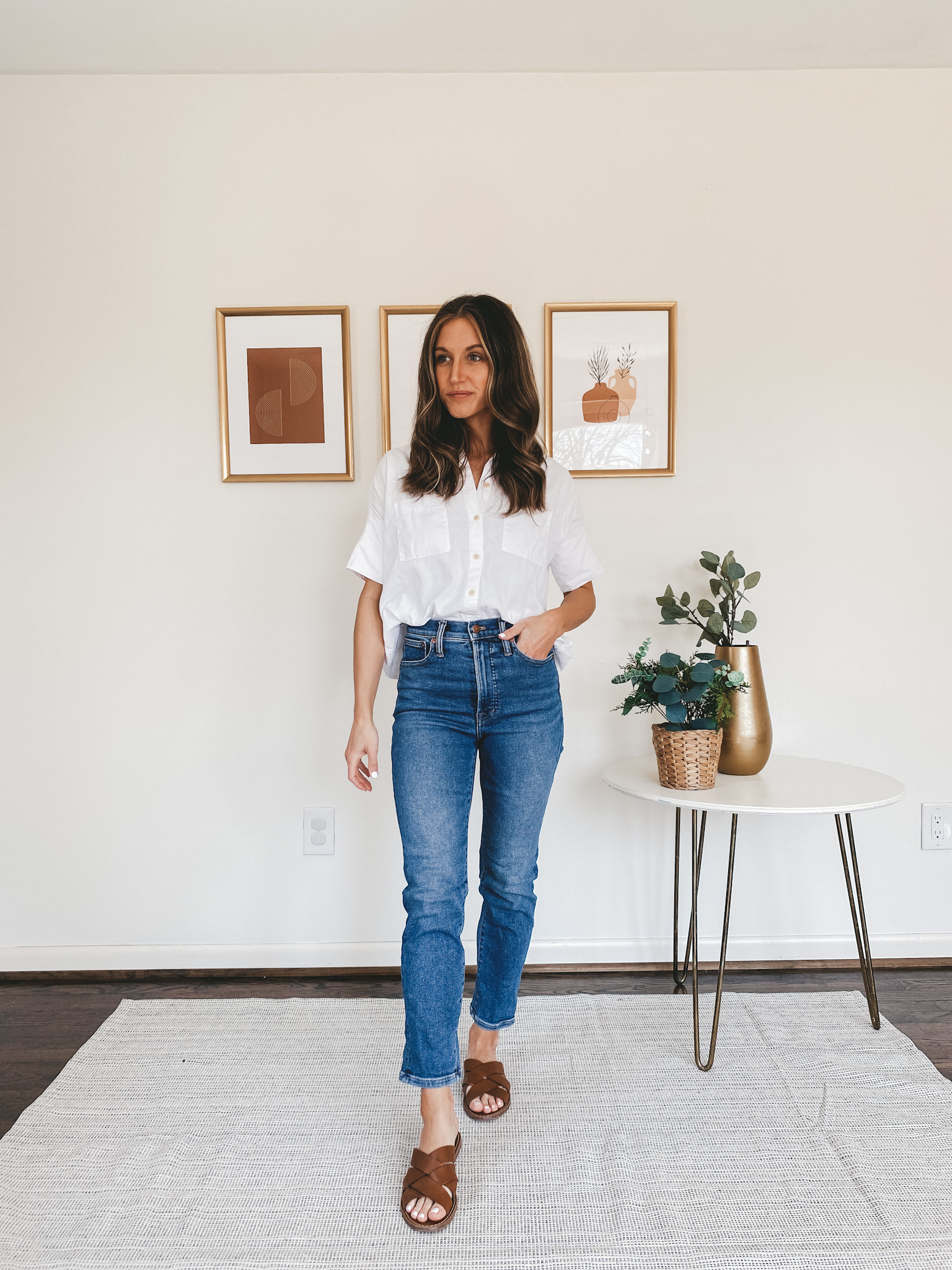 ashley wearing a white button down, mid-wash denim, and brown braided sandals