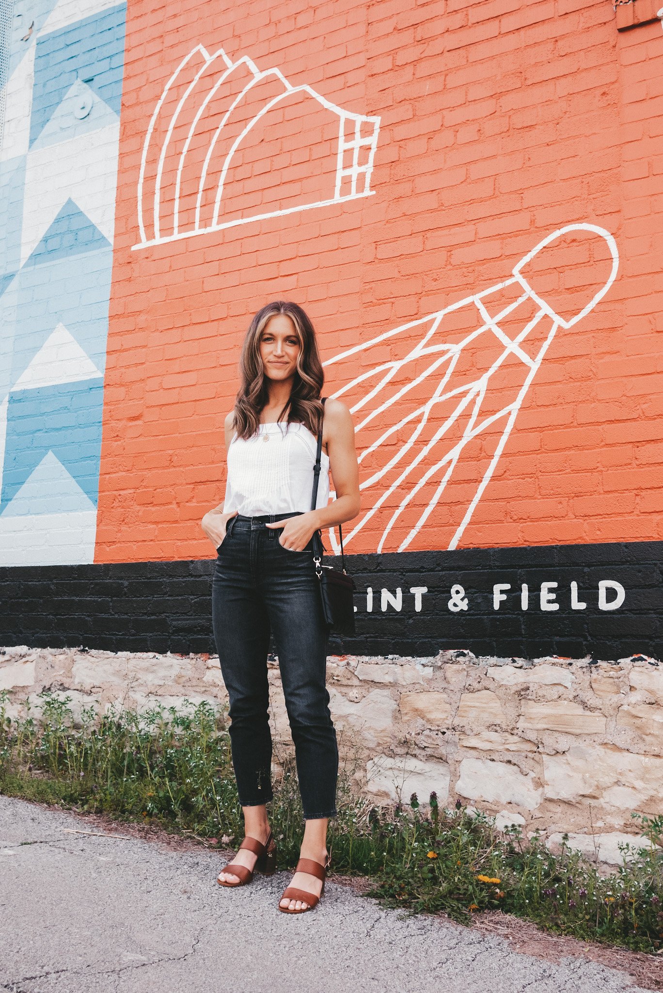 ashley wearing a white eyelet tank, black jeans, and brown block heeled sandals