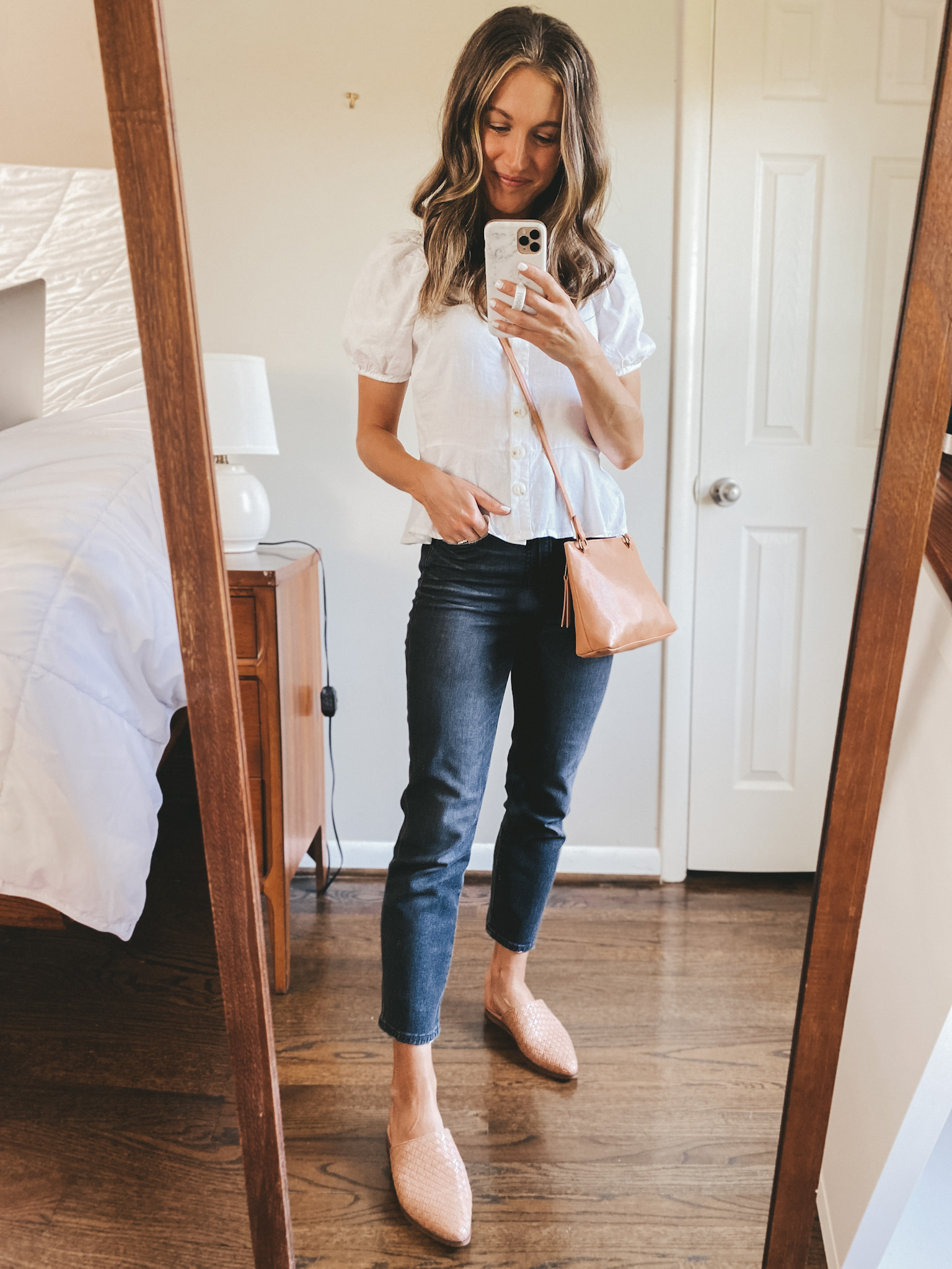ashley wearing a white puff sleeve shirt, washed black denim, and tan woven mules