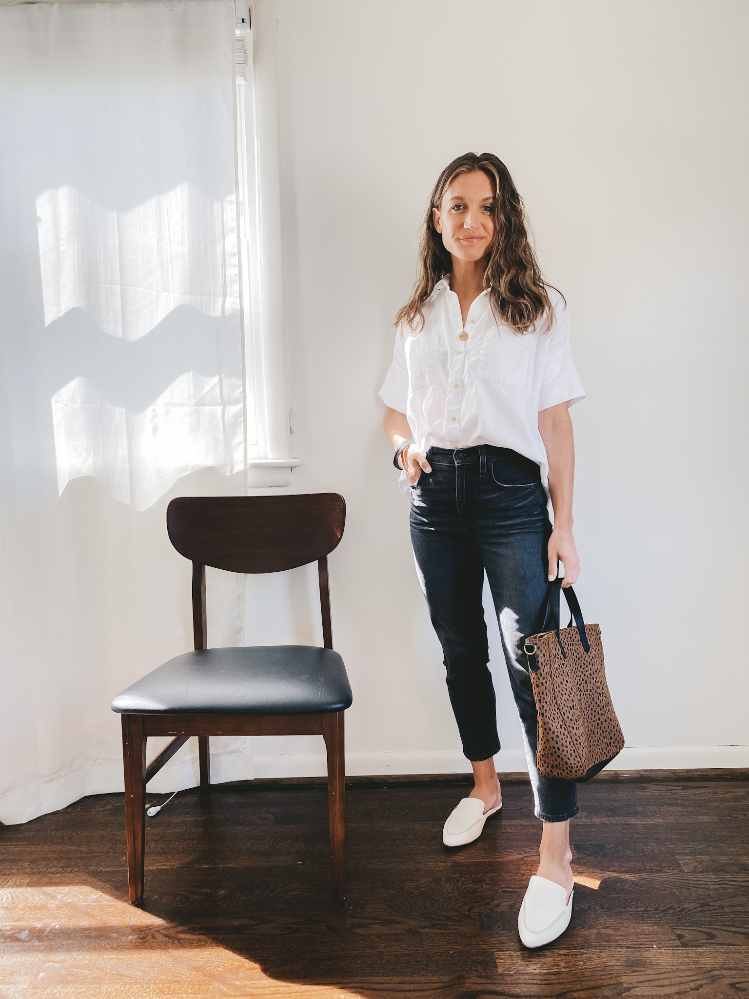 ashley wearing a short sleeved white button down, washed black denim, and white mules