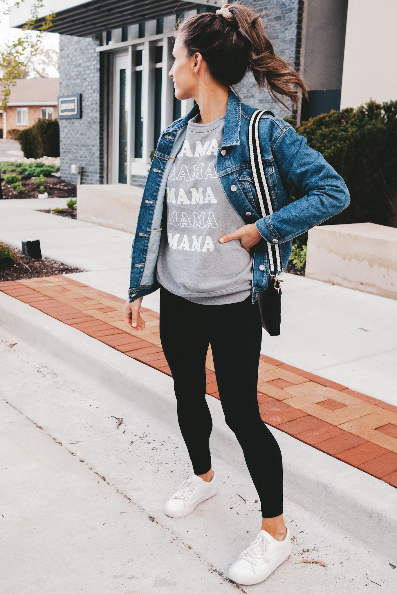 ashley wearing a graphic sweatshirt that says Mama, standing next to a curb