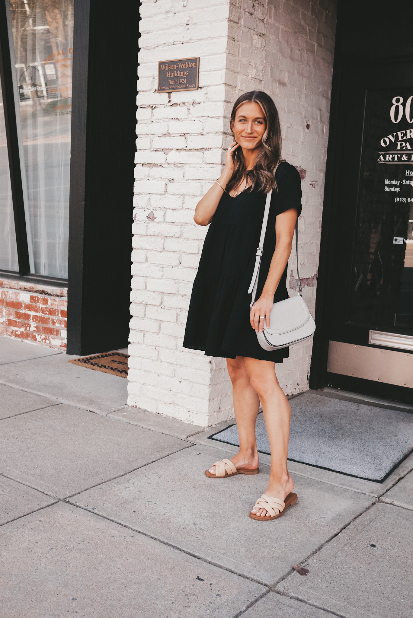 ashley wearing a black dress standing next to a store 