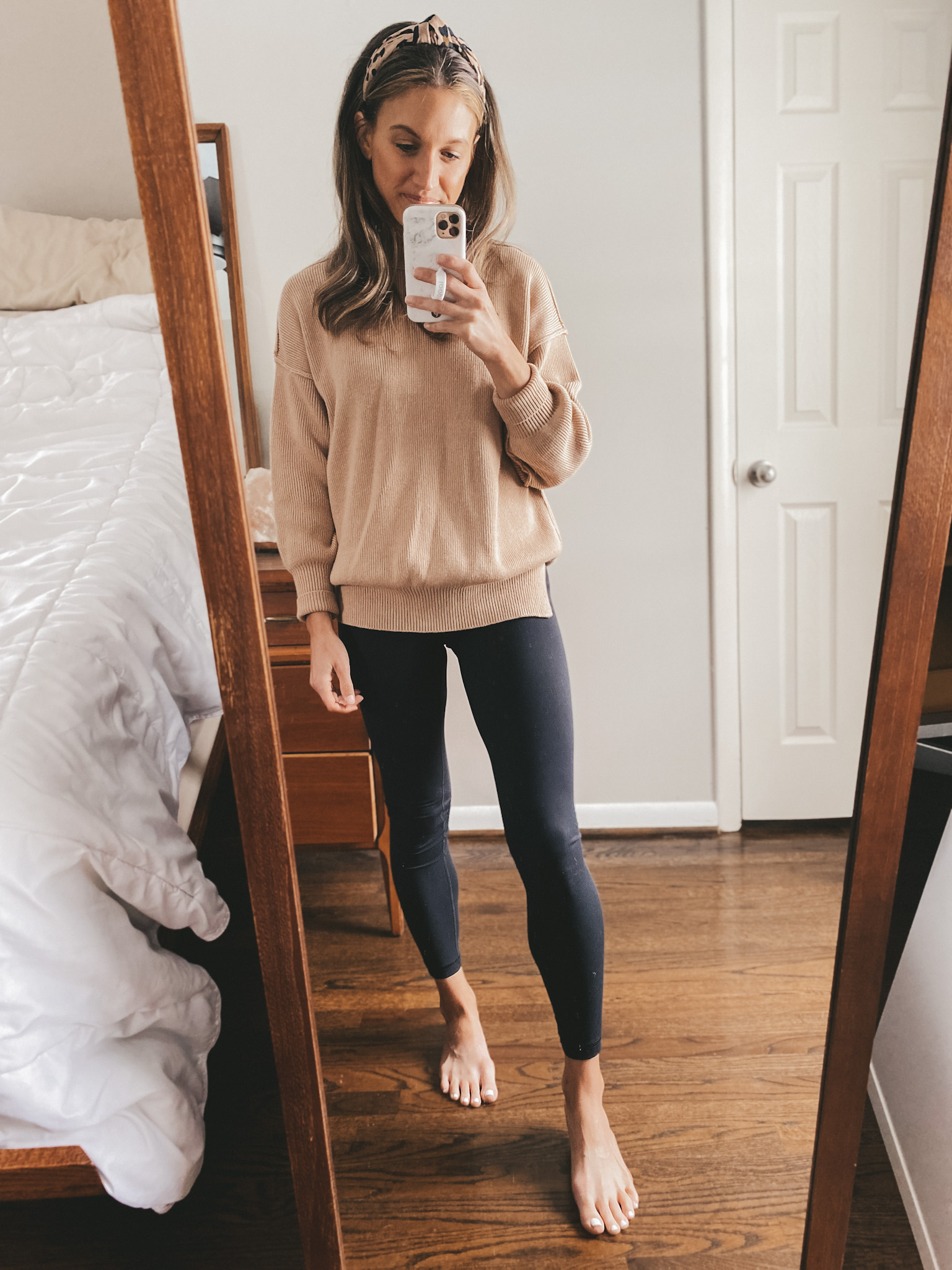 ashley wearing a tan oversized sweater, black leggings and a leopard knotted headband