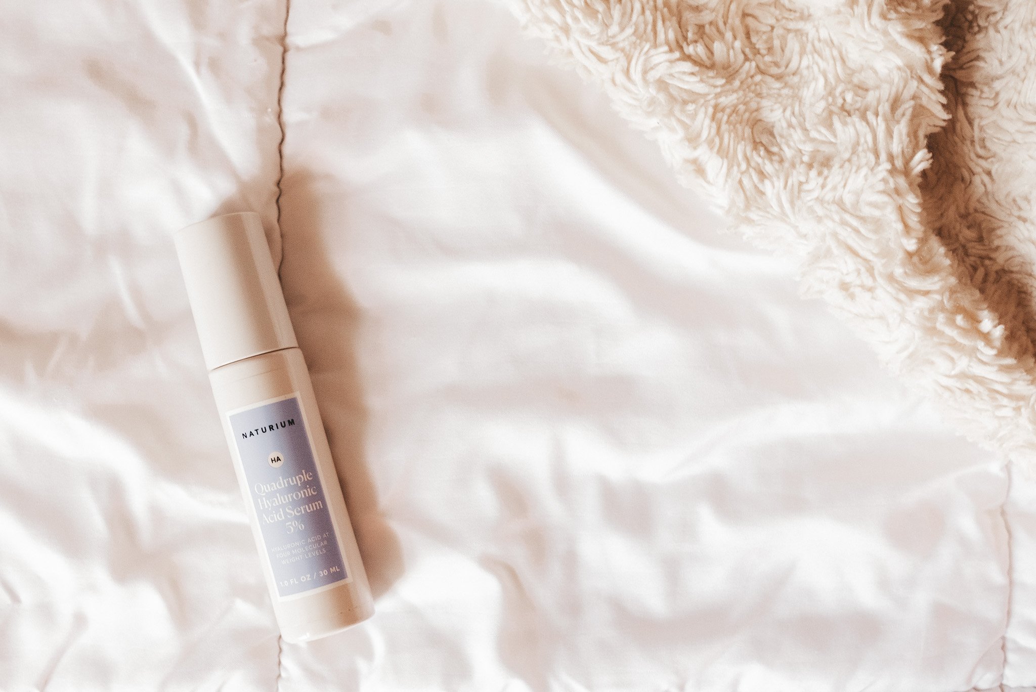 a bottle of Naturium Hyaluronic Acid on a white comfortor